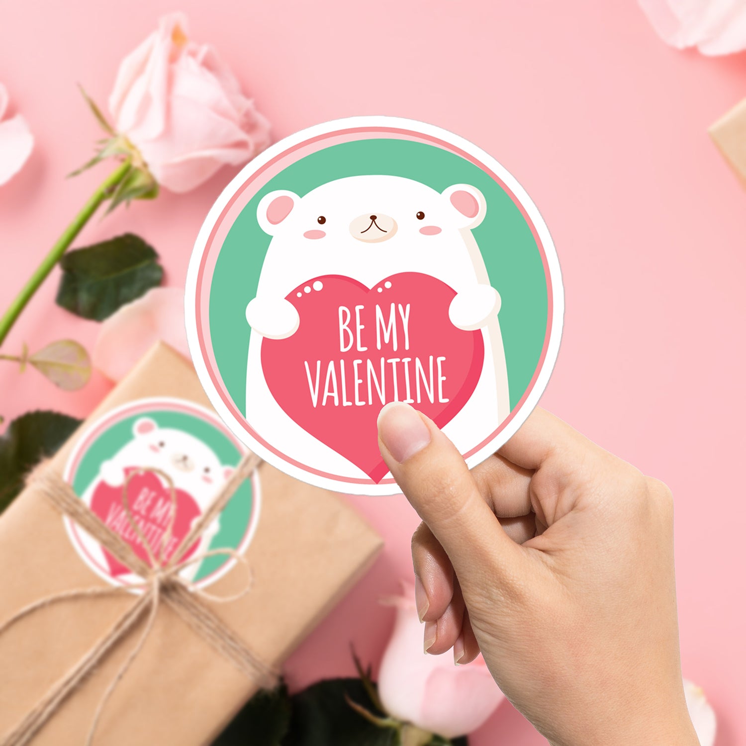 a hand holding a sticker with a bear holding a heart