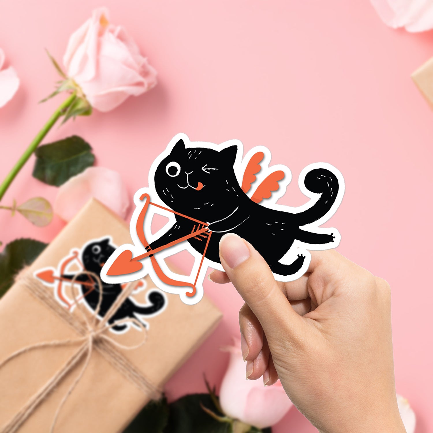 a hand holding a sticker of a black cat