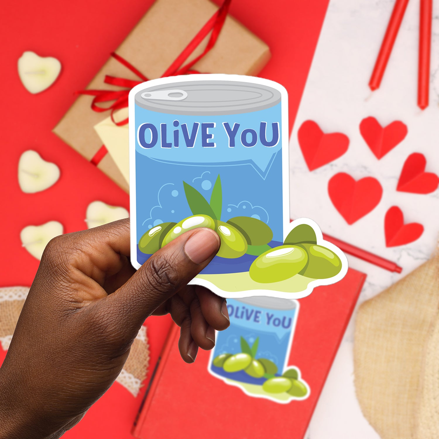 a hand holding a sticker with olives on it