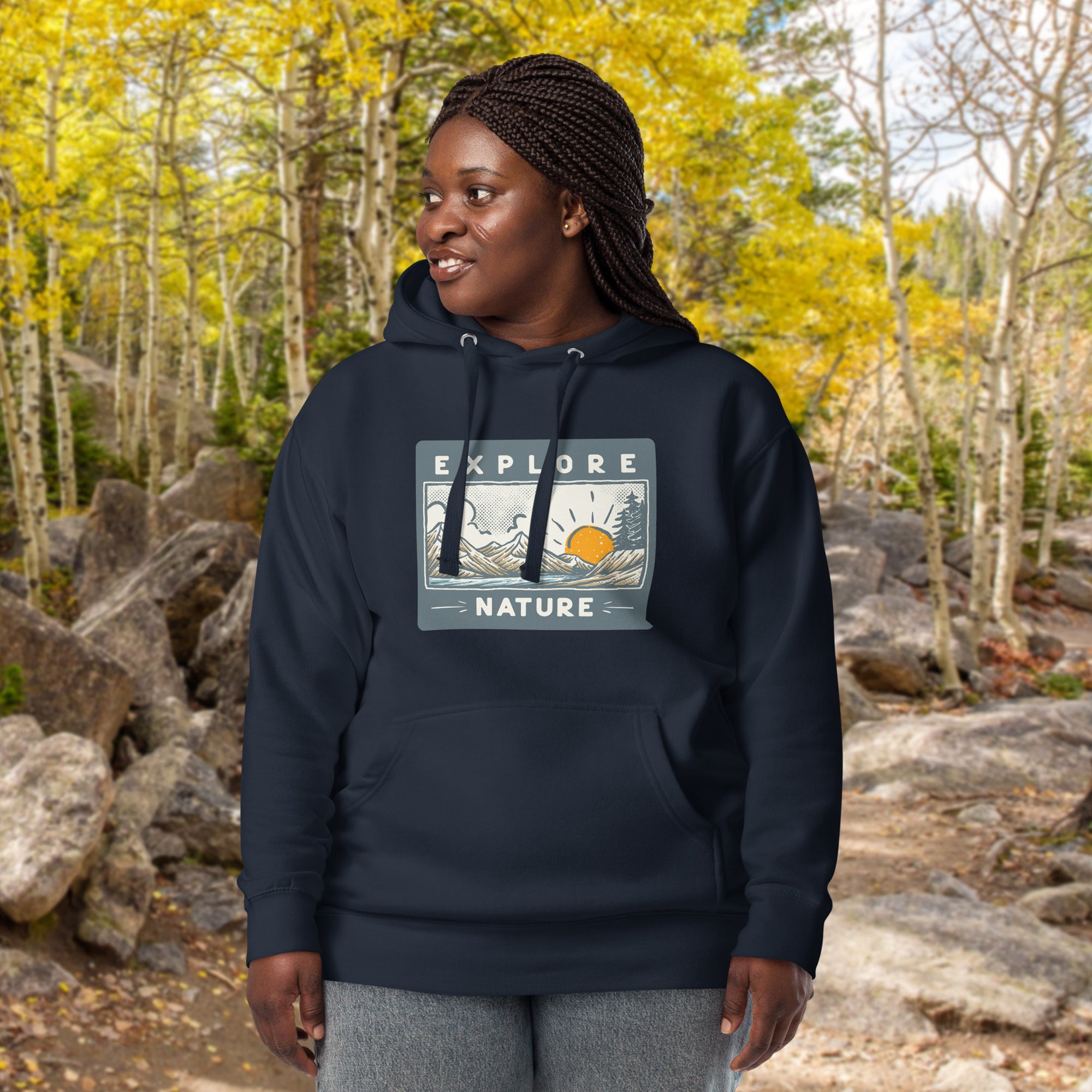 a woman in a blue hoodie stands in a wooded area