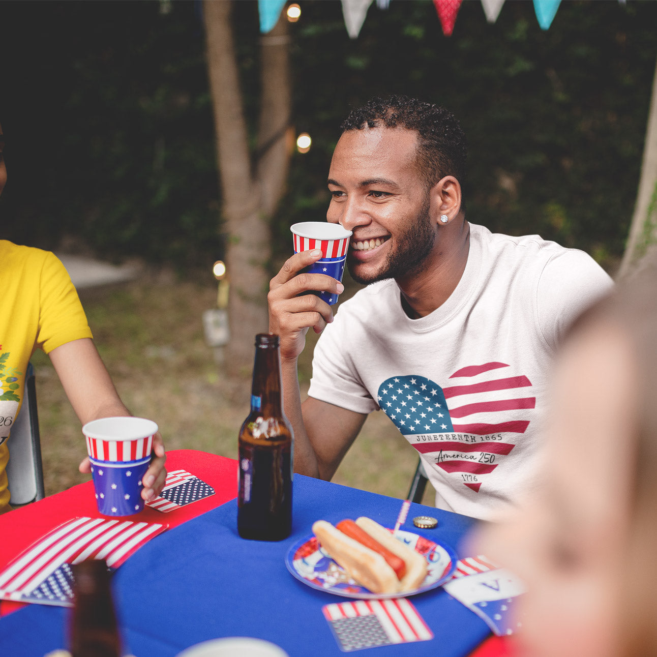 a man sitting at a table with a beer and hot dog
