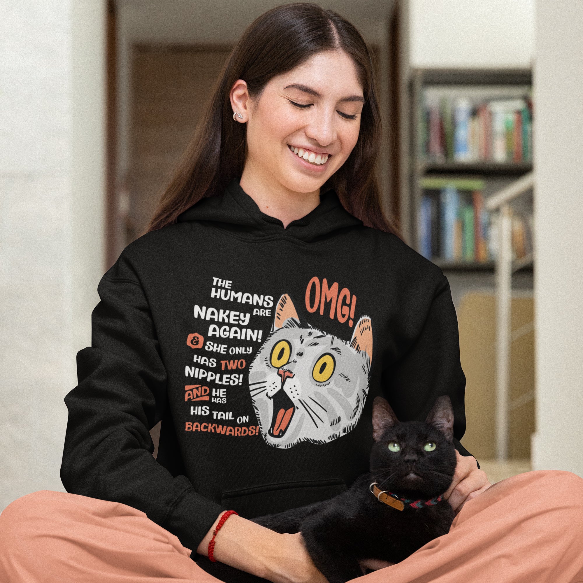 a woman in a black hoodie holding a black cat