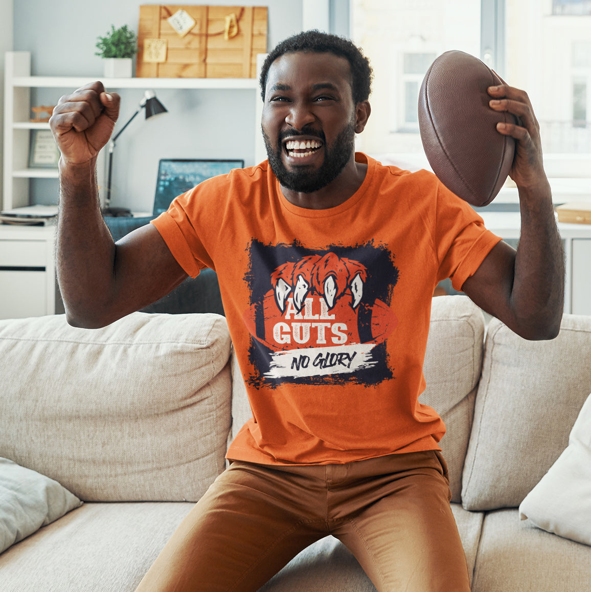 a man sitting on a couch holding a football