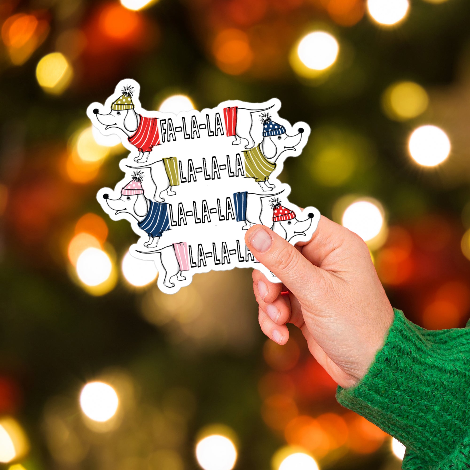 a person holding up some stickers with a christmas tree in the background