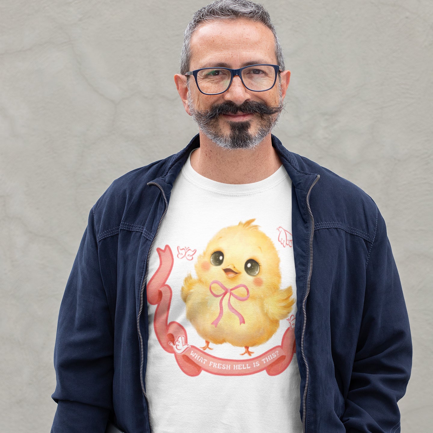 A man wearing a white t-shirt with a cartoon chicken graphic and a pink ribbon, standing against a gray background.
