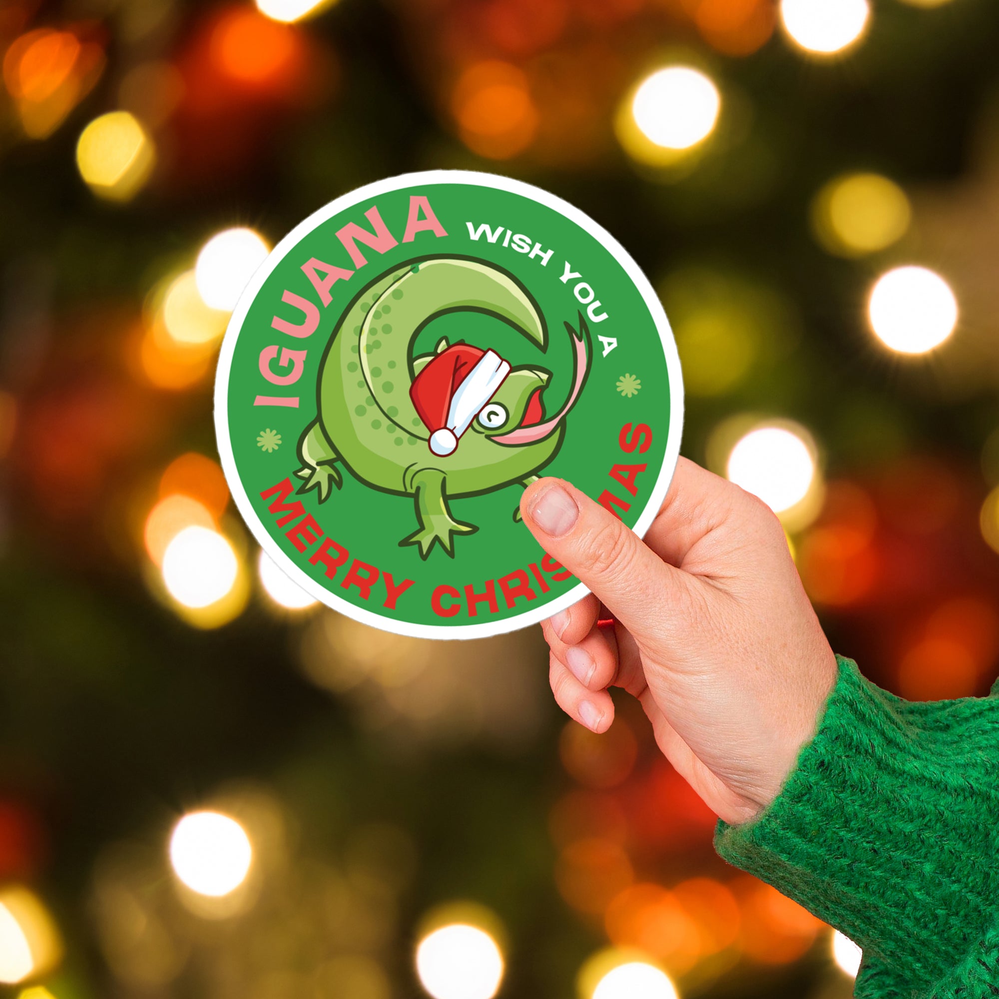 a person holding up a sticker with a christmas tree in the background