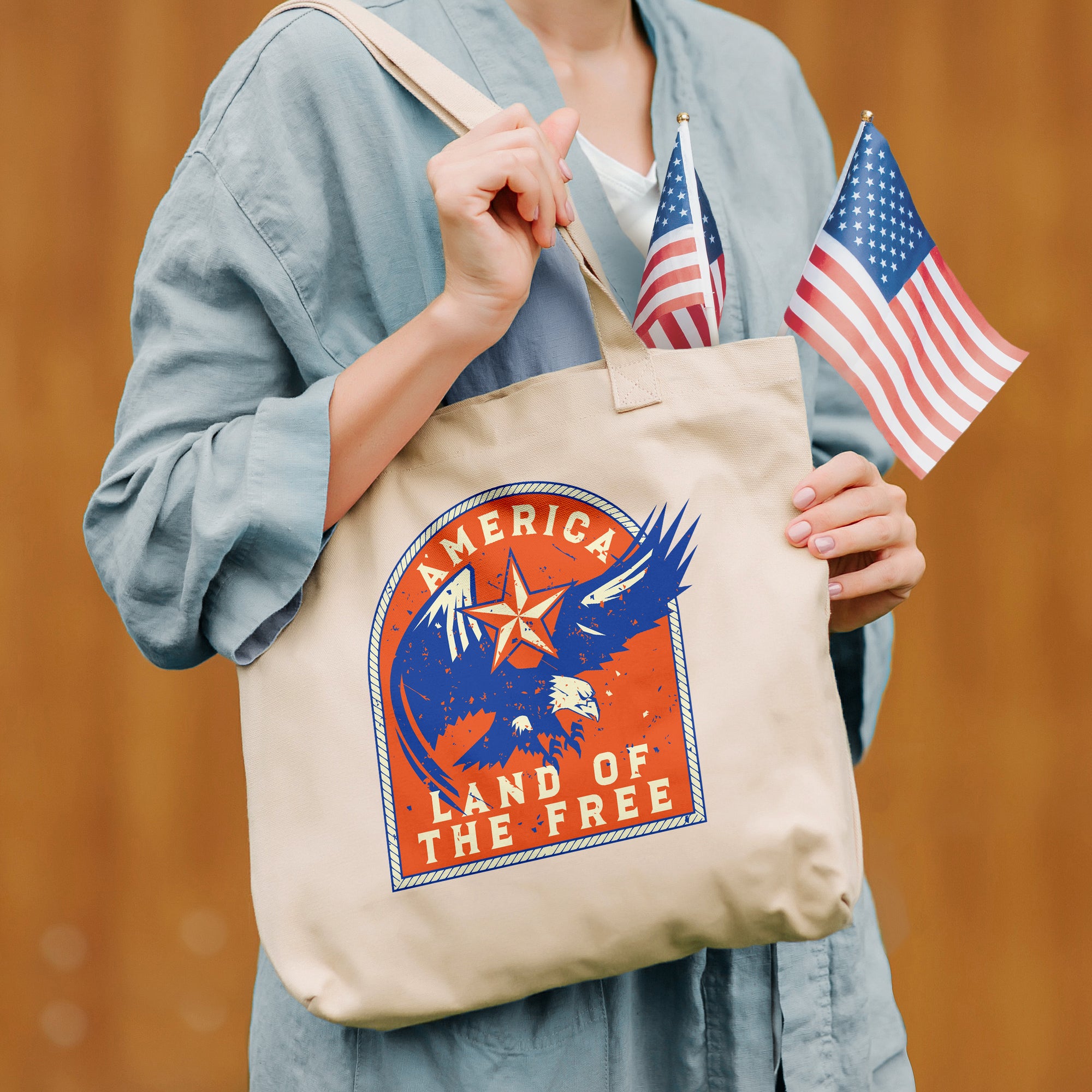 a woman holding a tote bag with an american land of the free design