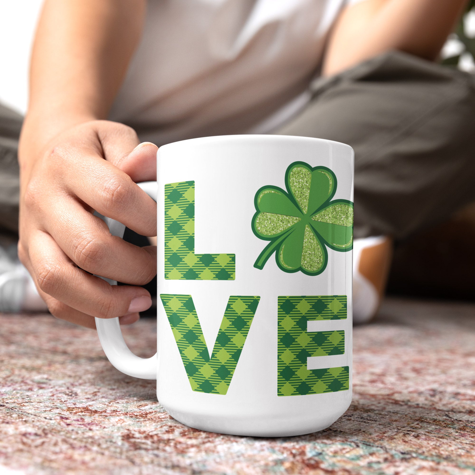 a person holding a coffee mug with a shamrock on it