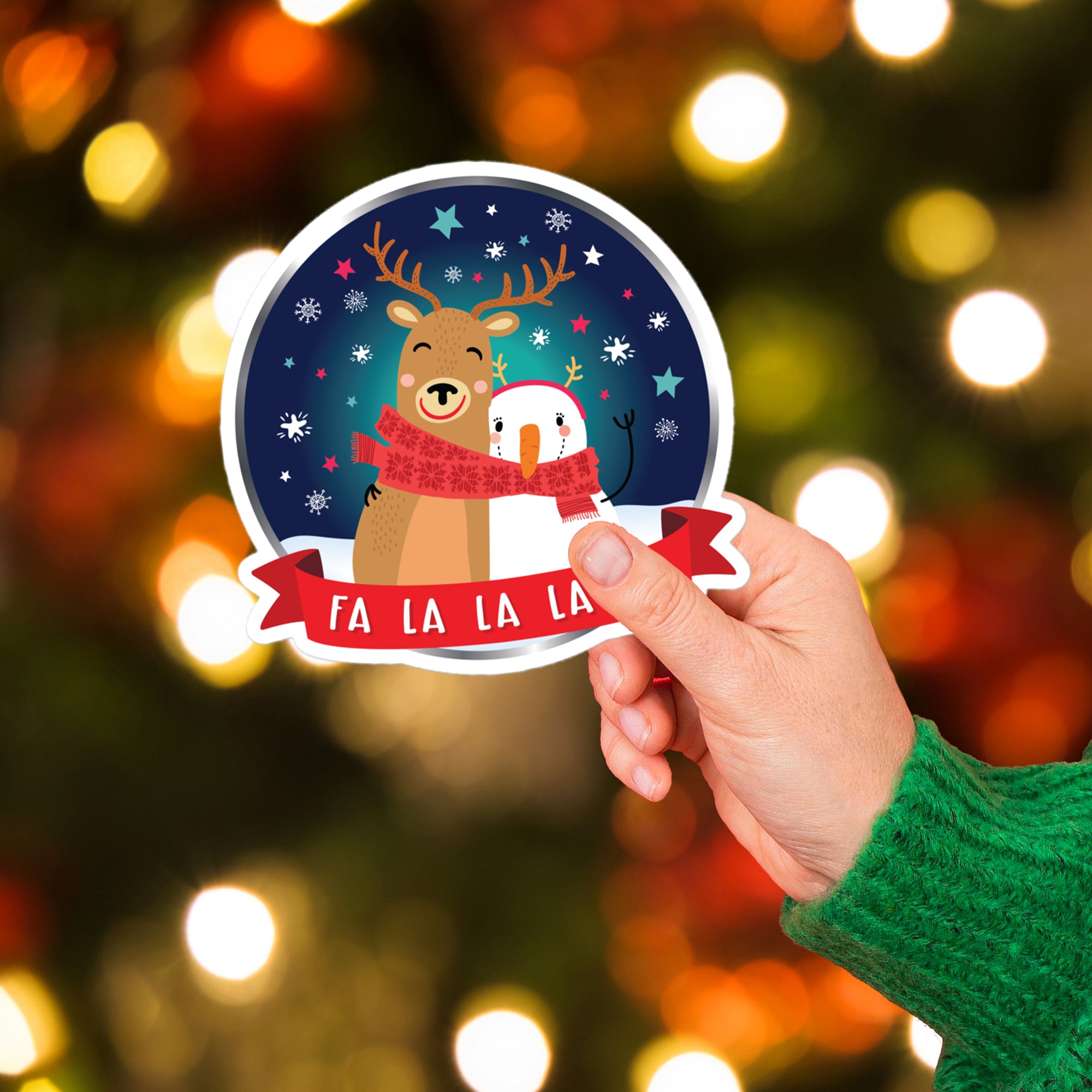 a hand holding a sticker with a reindeer and a snowman