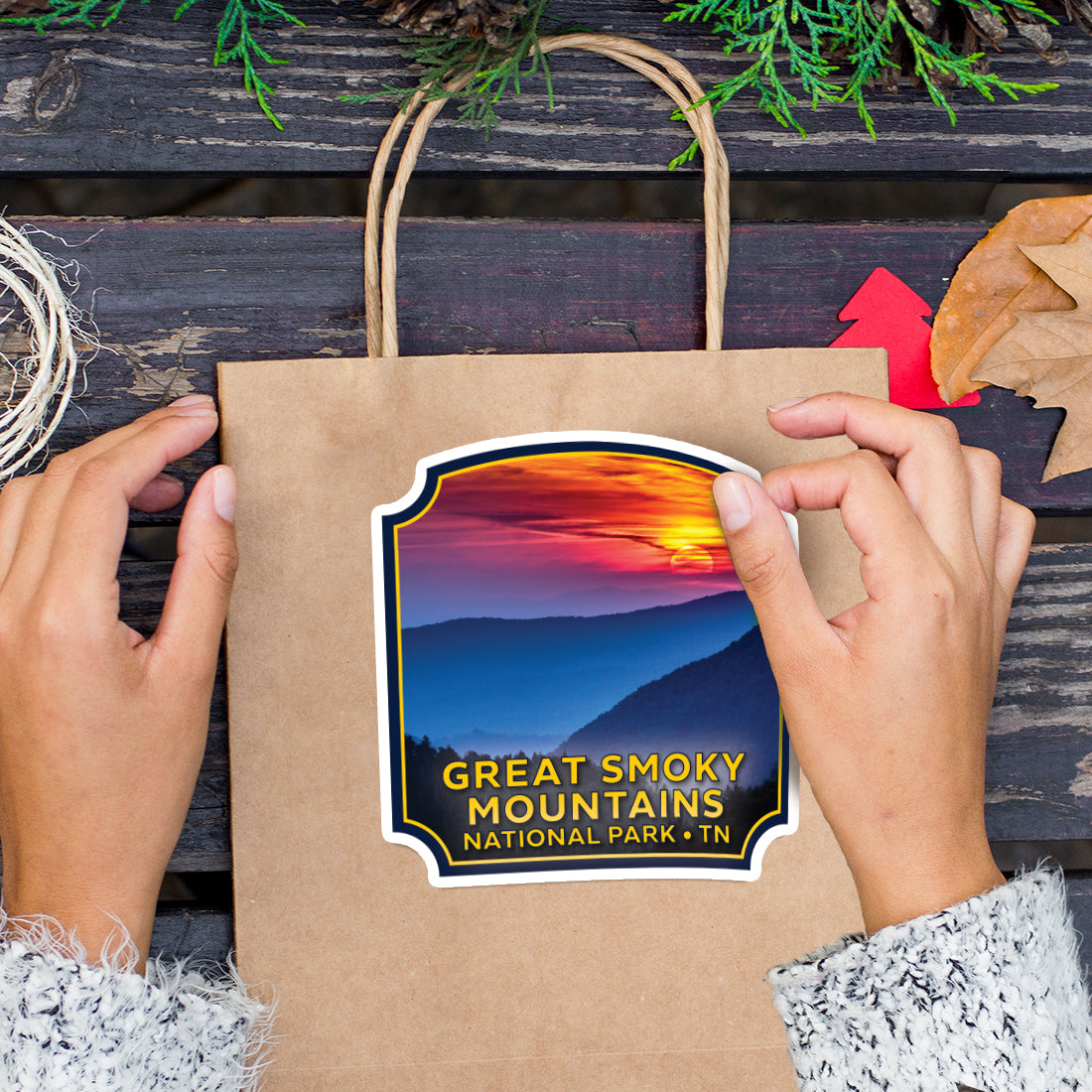 a person holding a brown bag with a great smoky mountains sticker on it