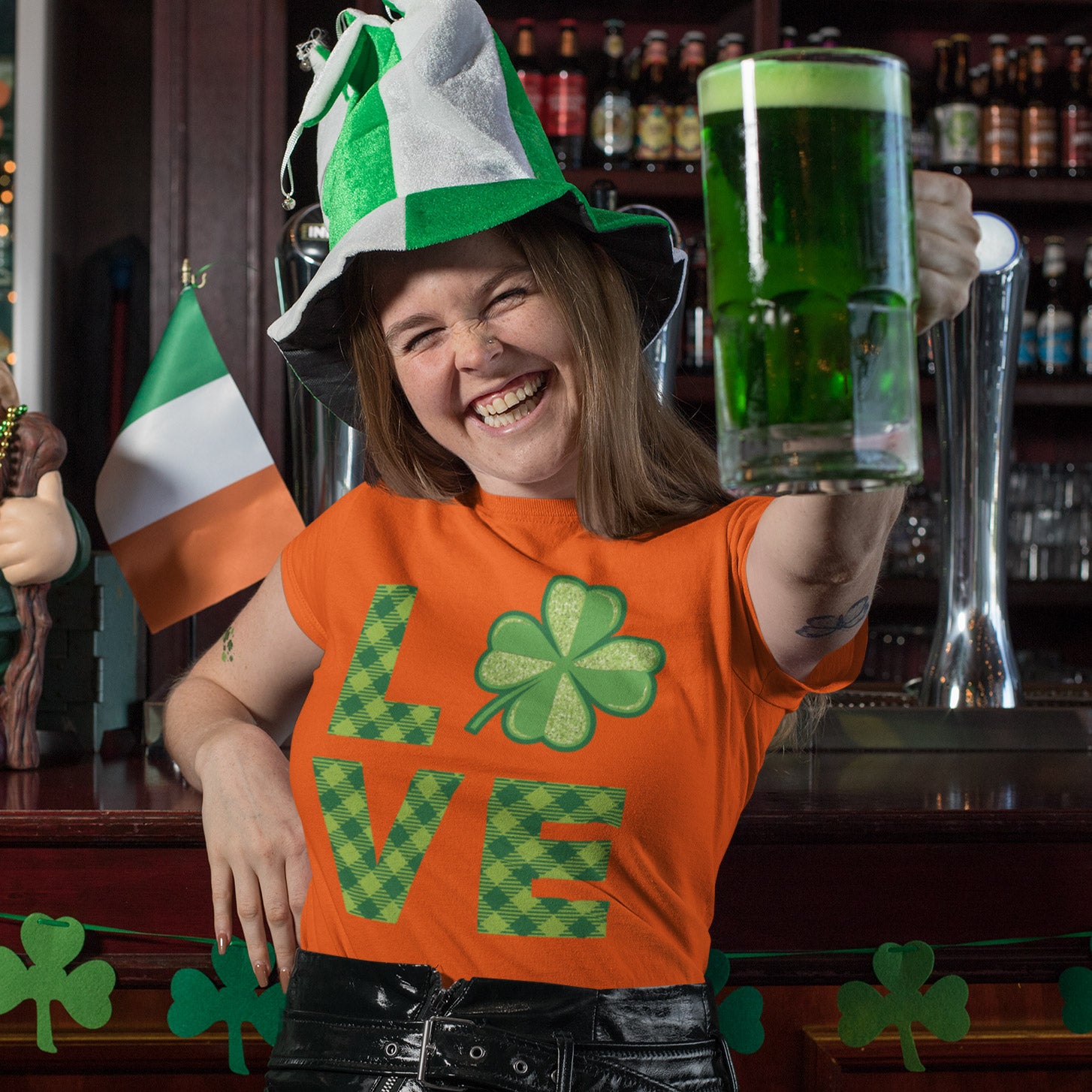 a woman in a st patrick's day t - shirt holding a glass of