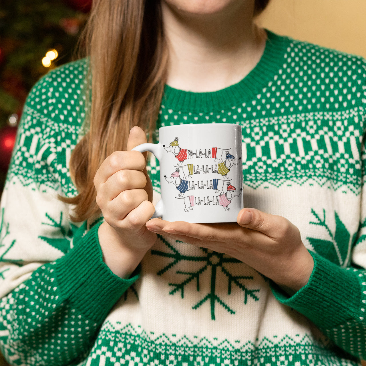 a woman holding a coffee mug in front of a christmas tree