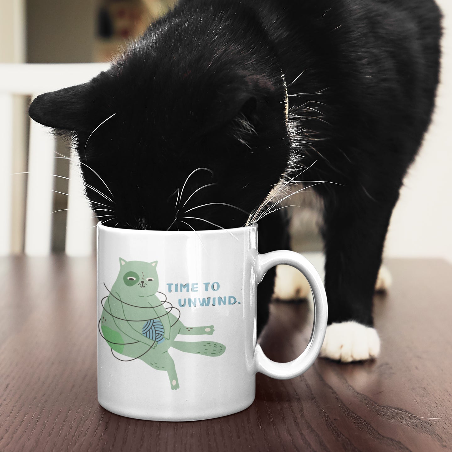 a black and white cat drinking out of a coffee cup