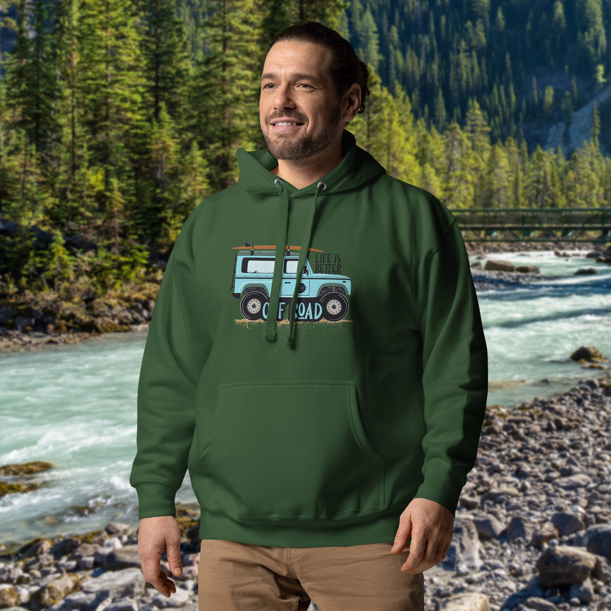 a man standing in front of a river wearing a green hoodie