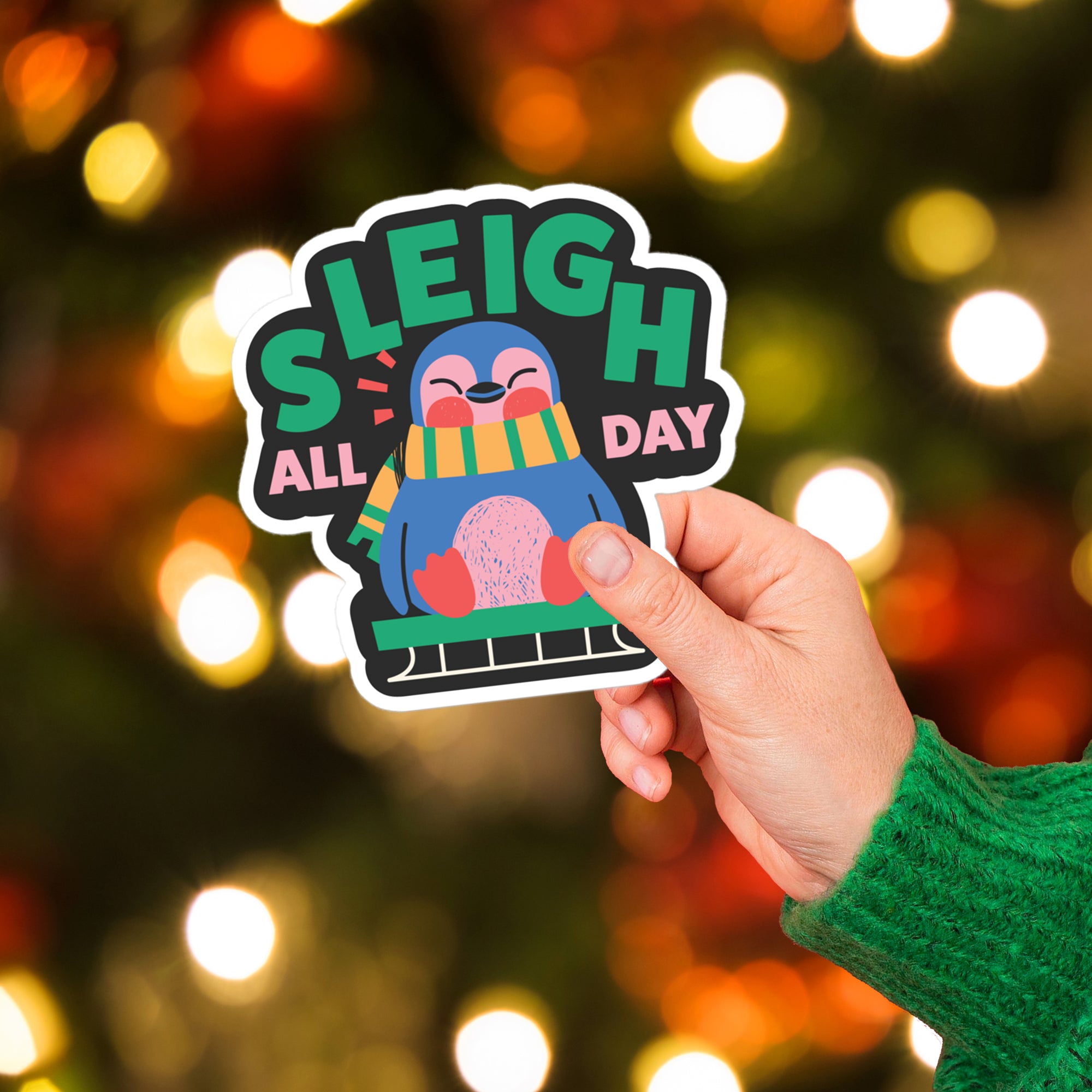 a hand holding a sticker with a christmas tree in the background