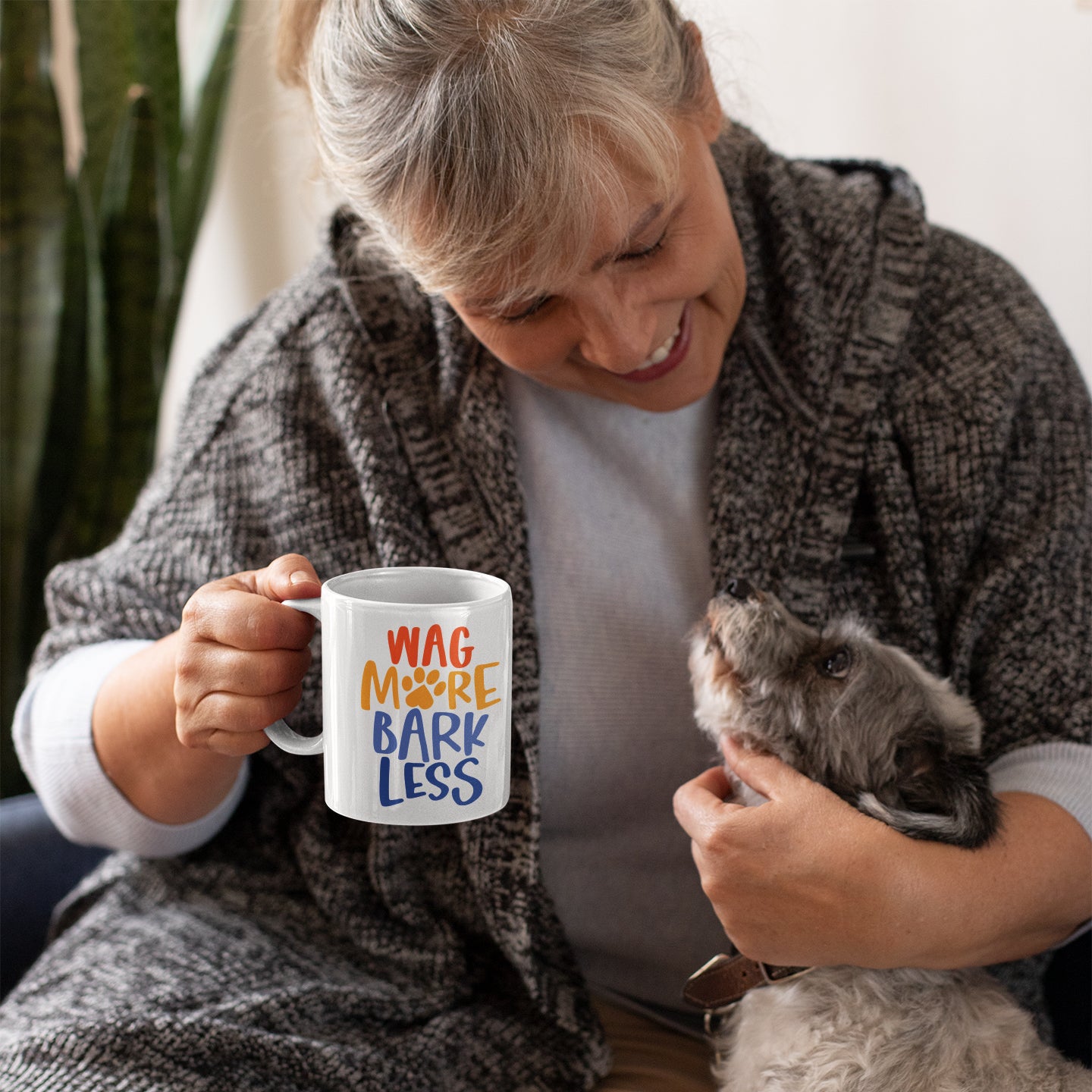 a woman holding a coffee mug with a dog inside