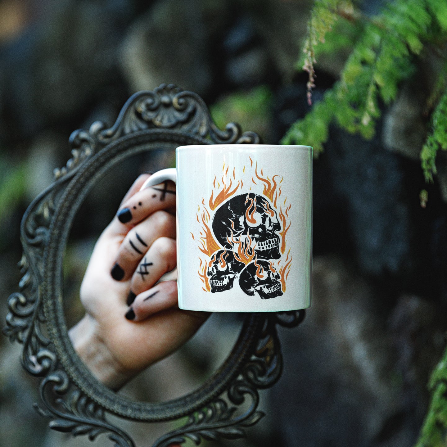 a woman's hand holding a coffee mug with a skull on it