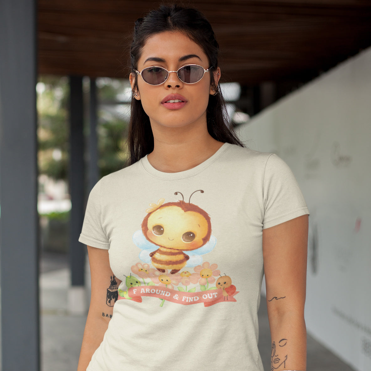 A woman wearing a white t-shirt with a cartoon bee graphic and the text "F. A. R. O. W. OUT" printed on it.