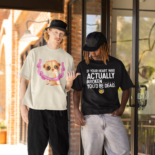 Two men standing outside a building, one wearing a white t-shirt with a cartoon meerkat and the other wearing a black t-shirt with a humorous text.