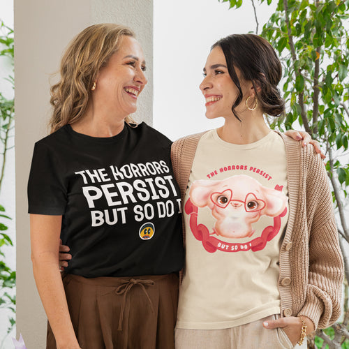 Two women standing together, smiling and posing for a photo. They are wearing T-shirts with humorous text and graphics.