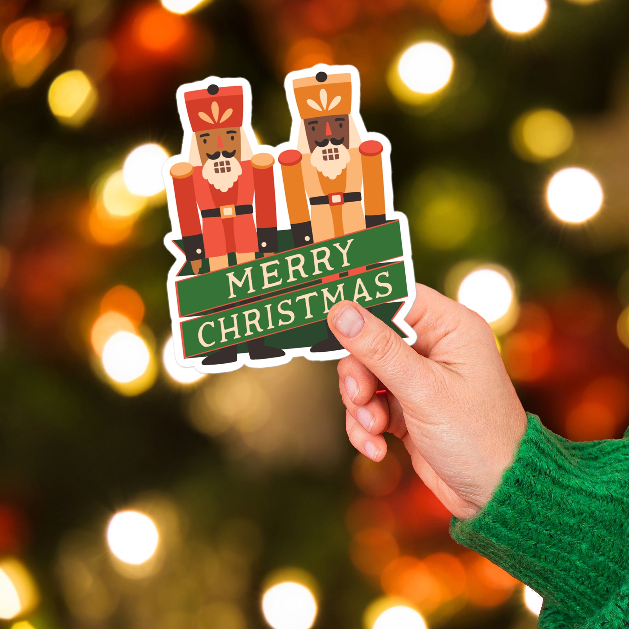 a hand holding a christmas sticker with a christmas tree in the background