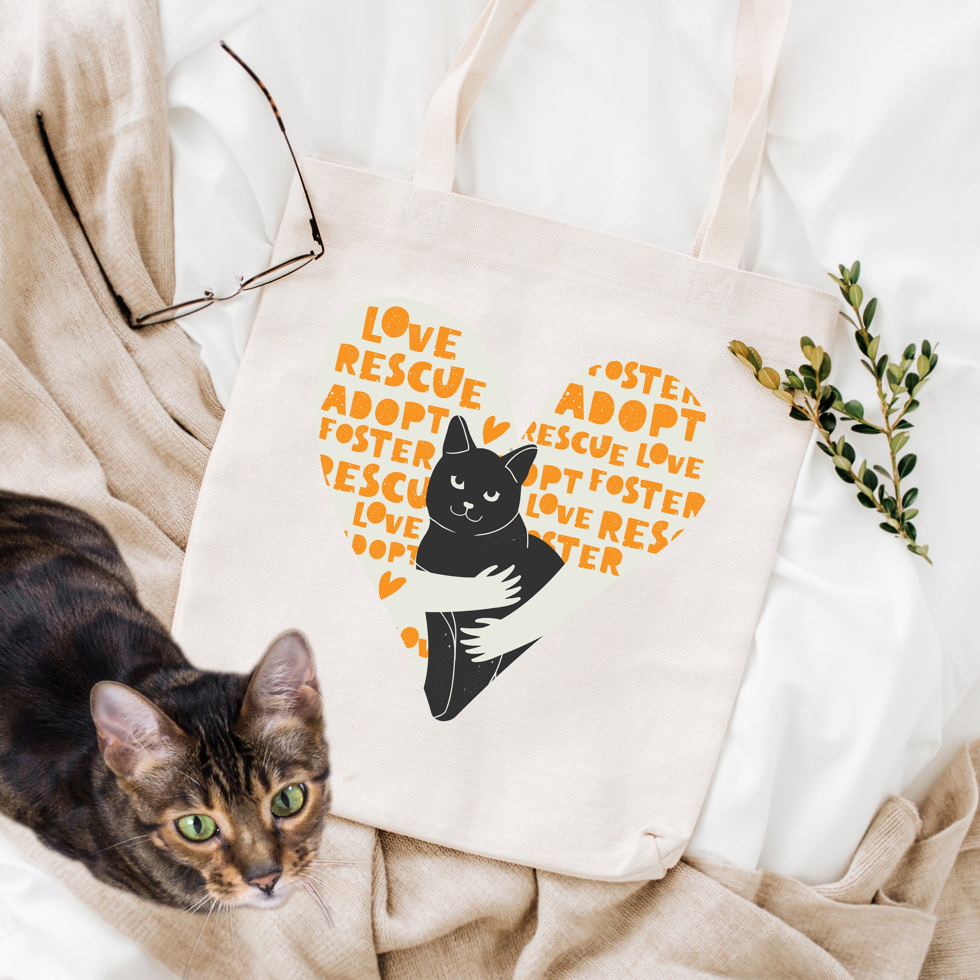 a cat laying on top of a bed next to a tote bag