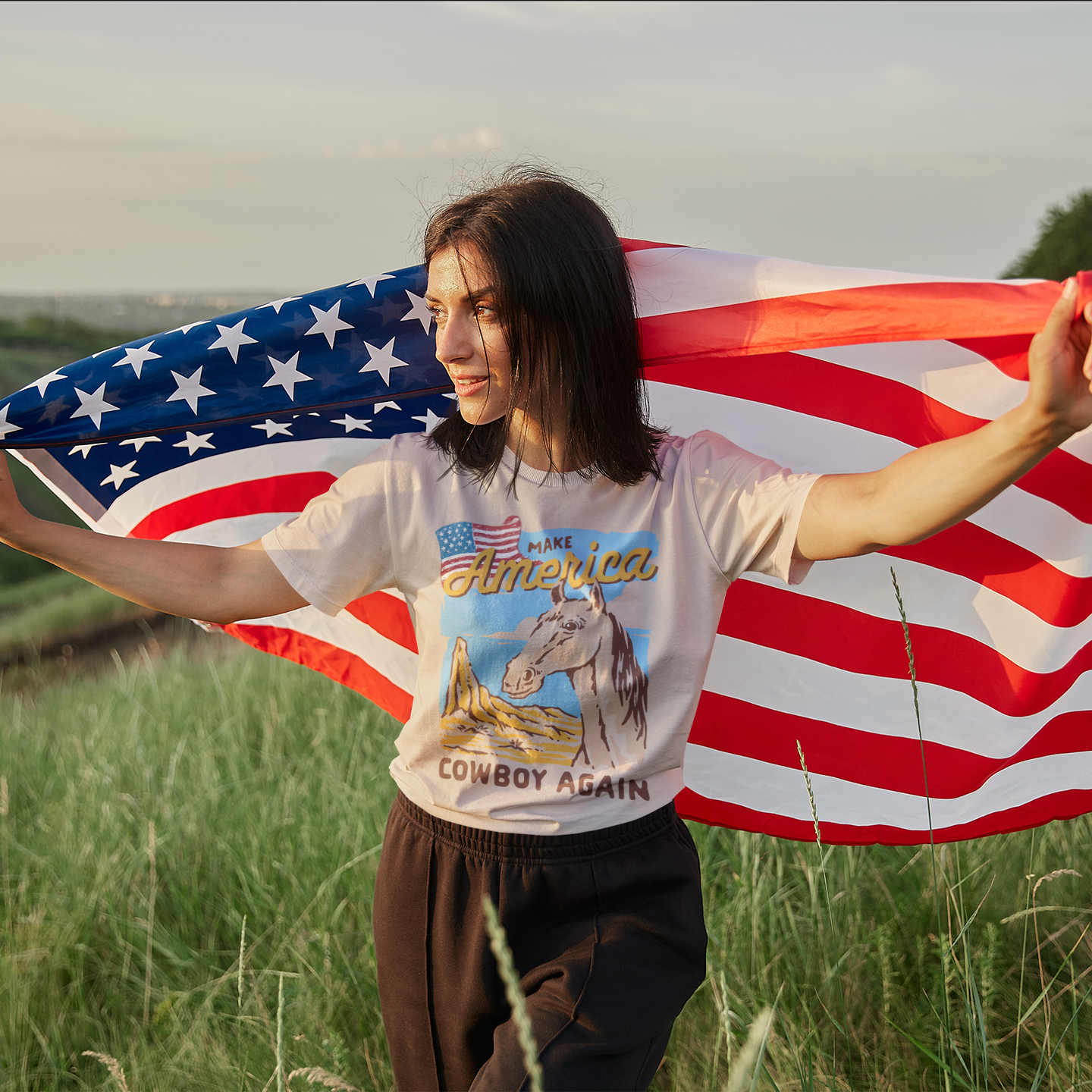 a woman holding an american flag in a field