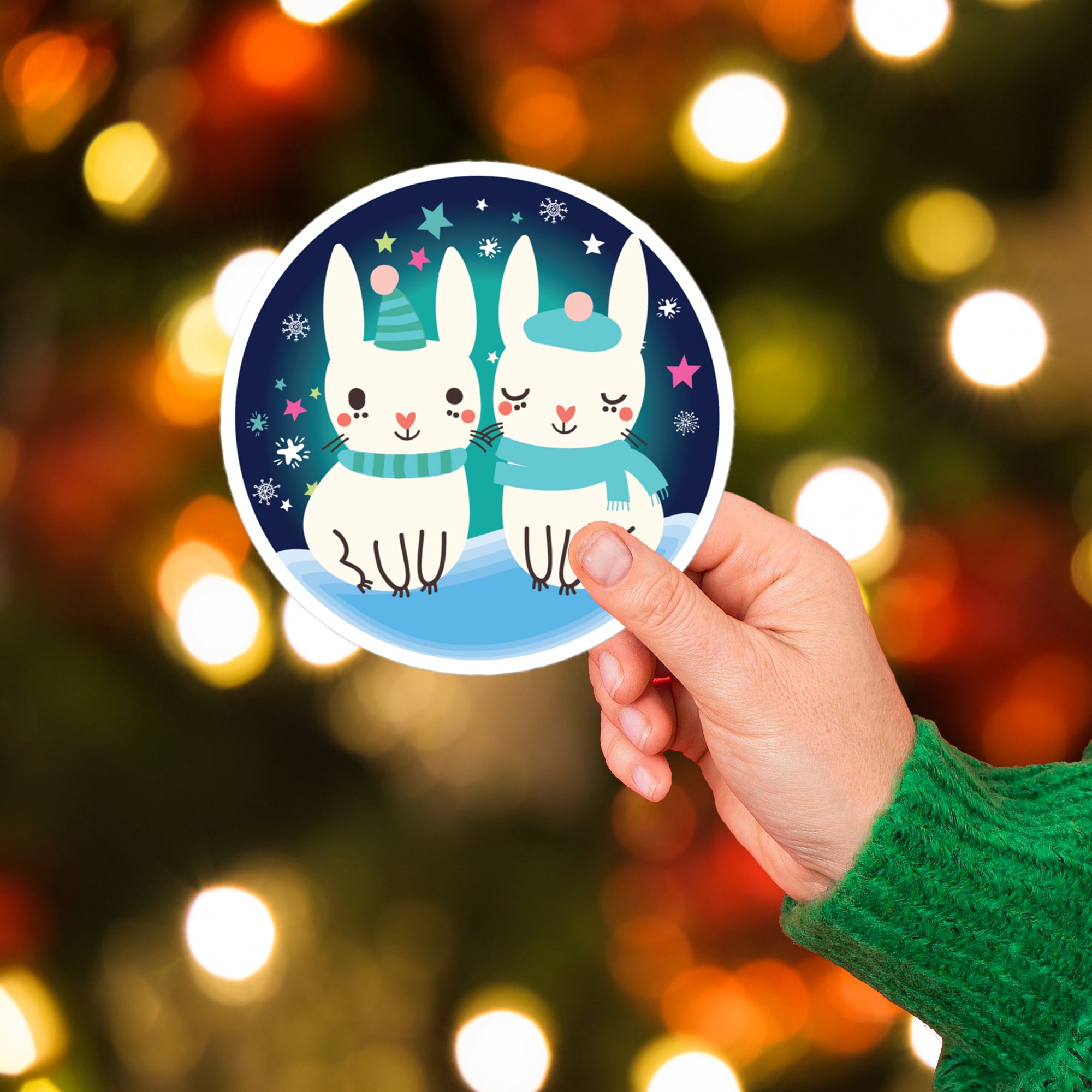 a person holding up a sticker with two rabbits on it