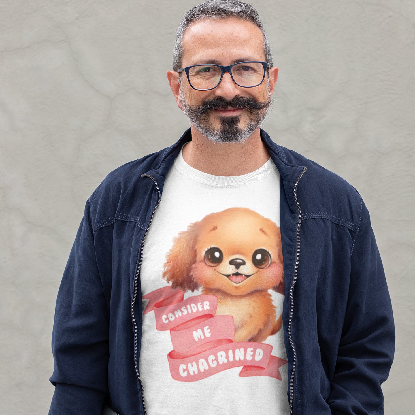 A man wearing glasses and a blue jacket is standing in front of a gray wall, wearing a white t-shirt with a cartoon dog and the text "Considering me Choked" printed on it.