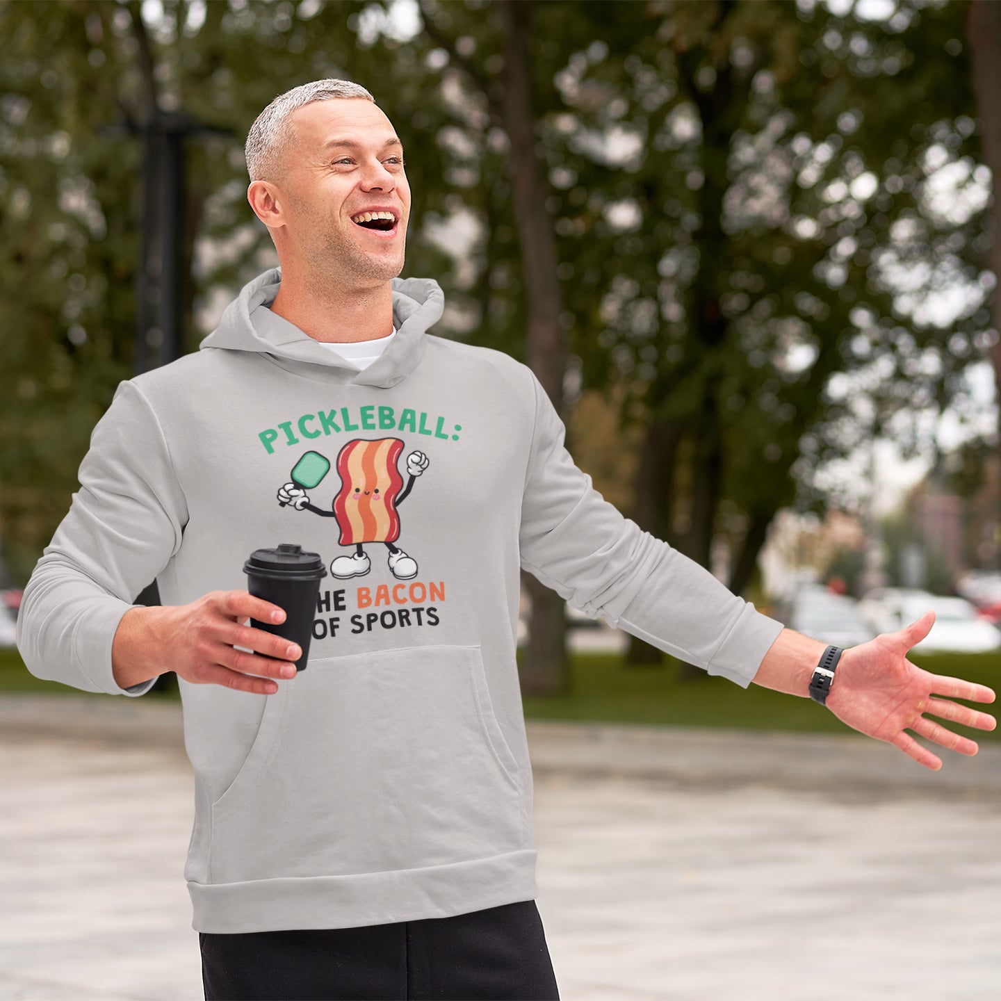 a man in a grey hoodie holding a black cup