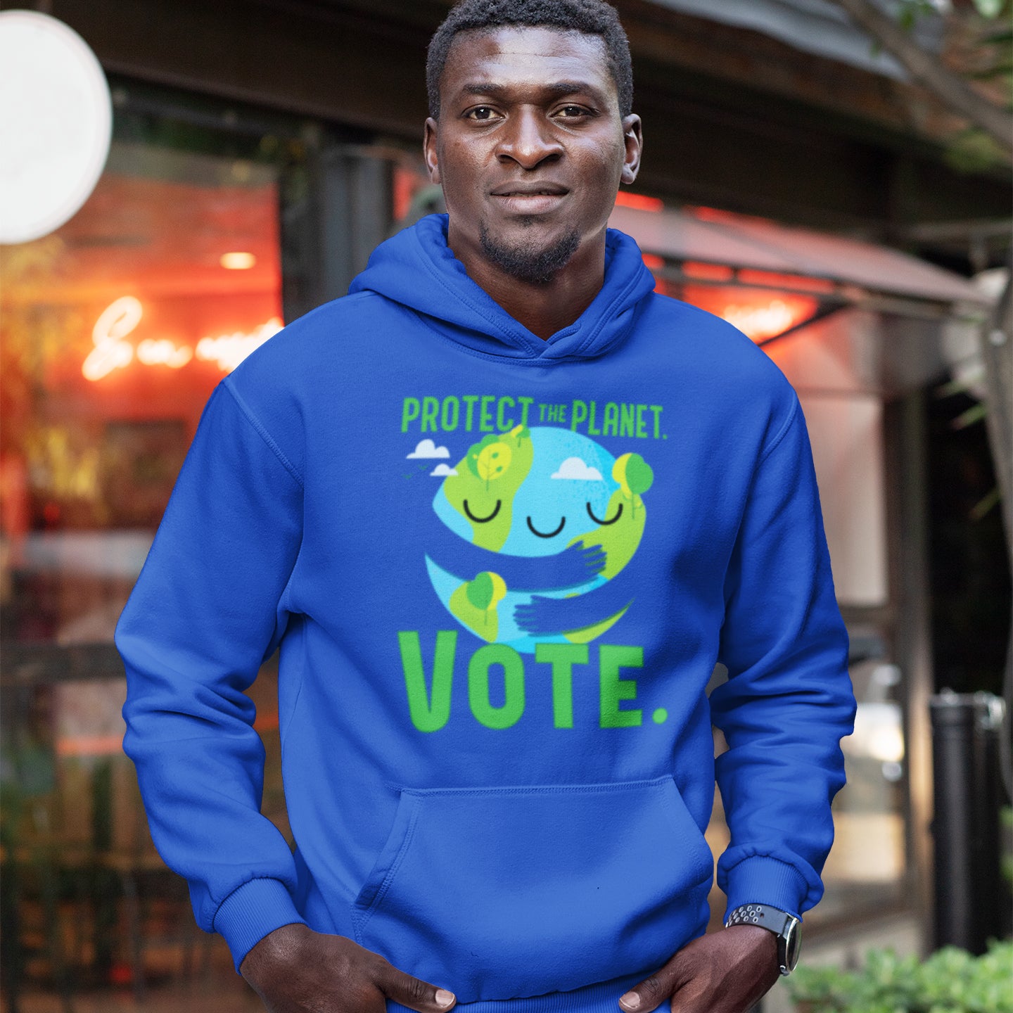 a man wearing a blue hoodie that says protect planet vote