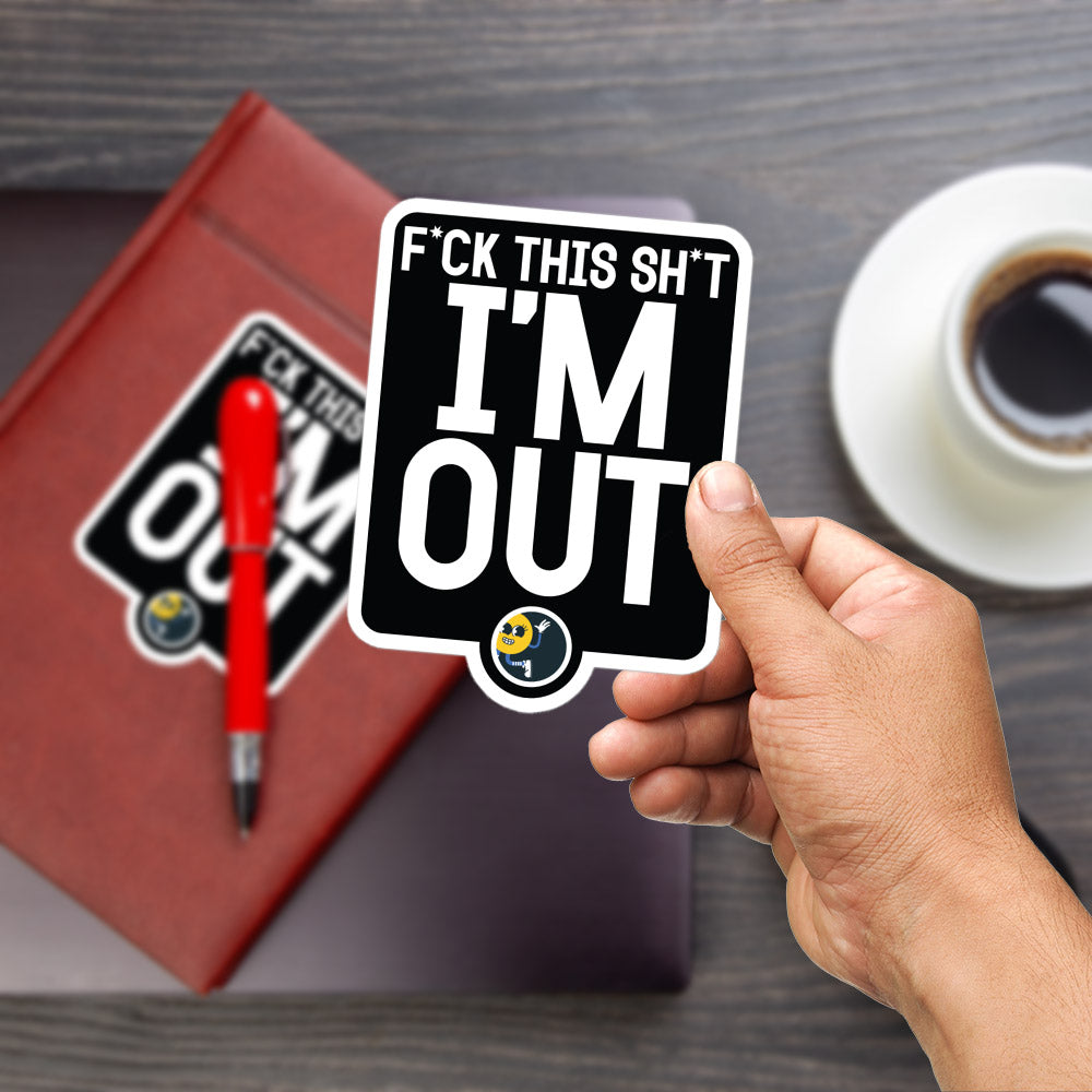 A person's hand is holding a sticker with the text "F*CK THIS SH*T I'M OUT" on a wooden surface, with a red pen and a cup of coffee in the background.