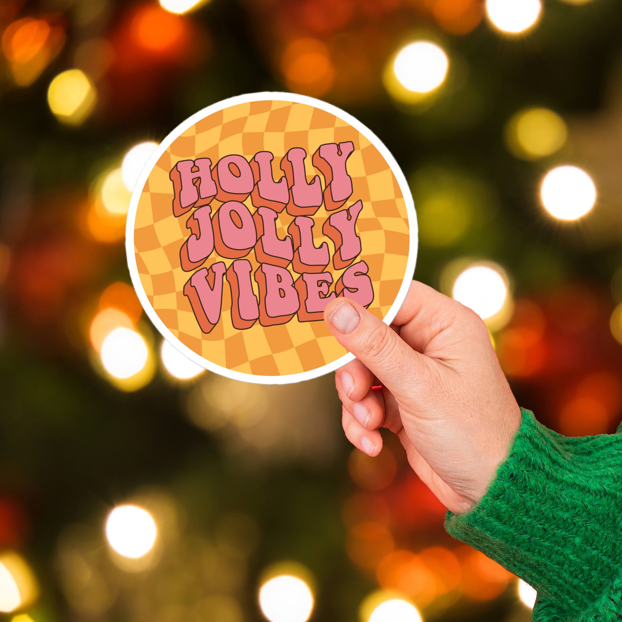 a hand holding a sticker that says holly jolly vibe