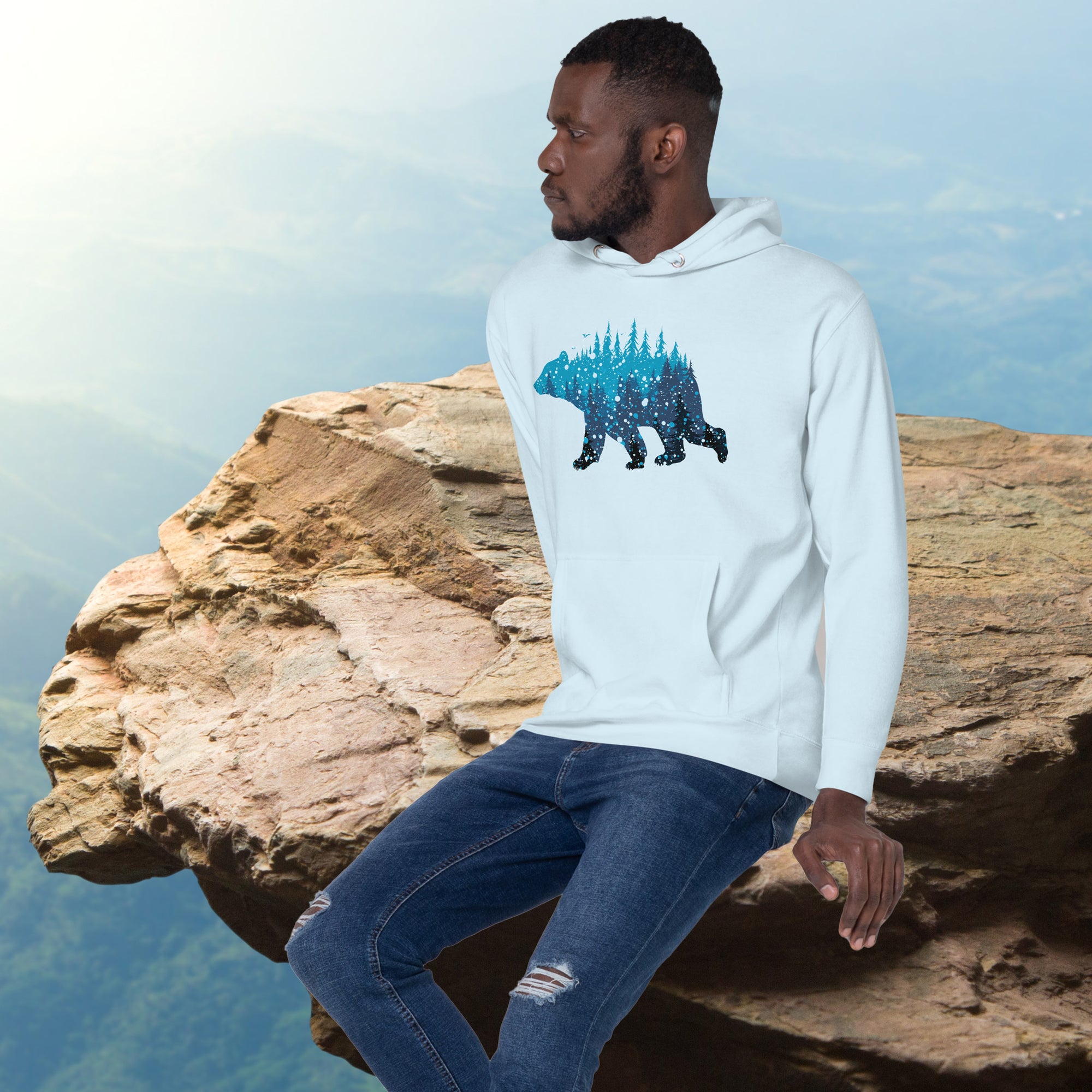 a man sitting on top of a cliff wearing a hoodie