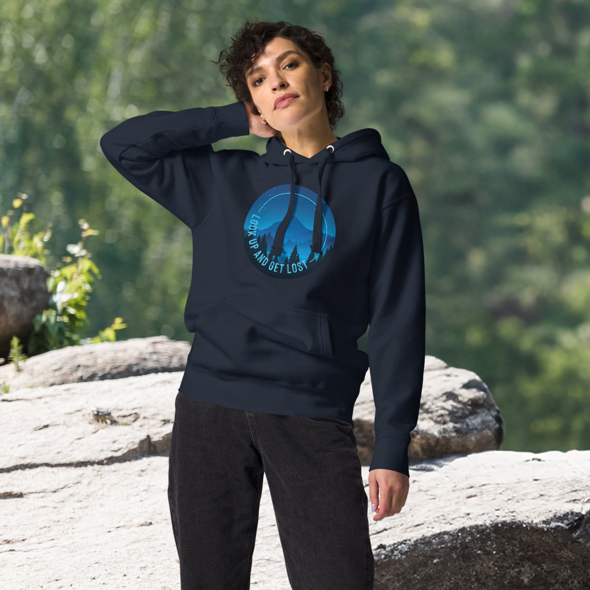 a woman in a blue hoodie stands on a rock