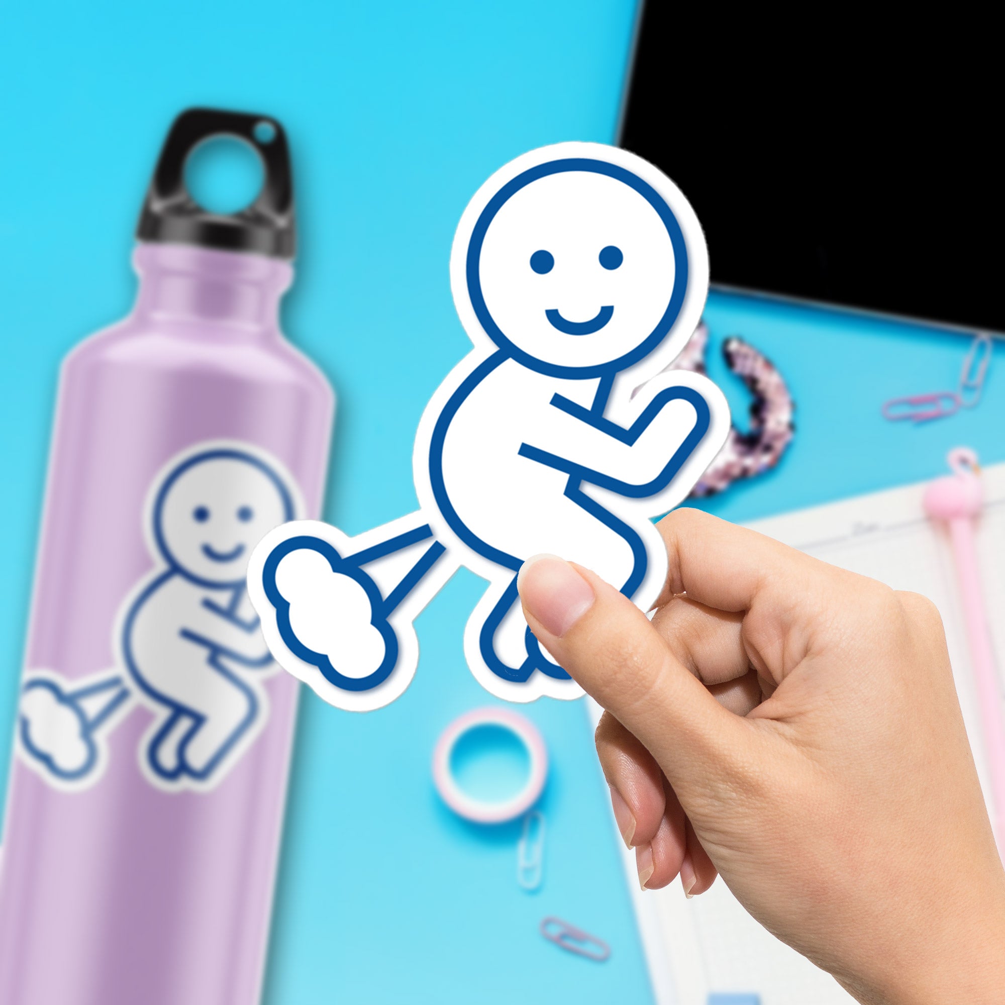 a hand holding a sticker of a baby on a blue background