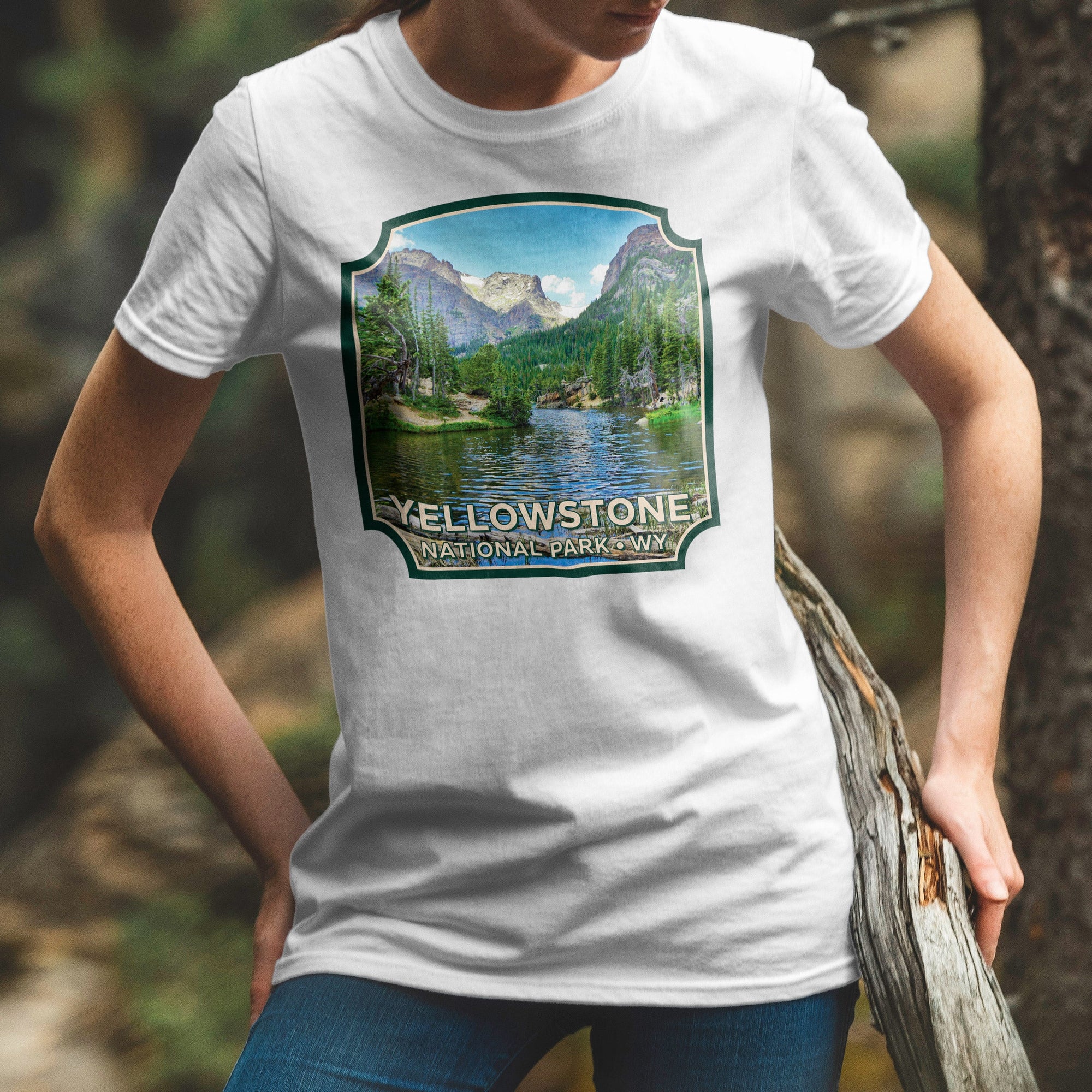 a woman wearing a yellowstone t - shirt standing next to a tree