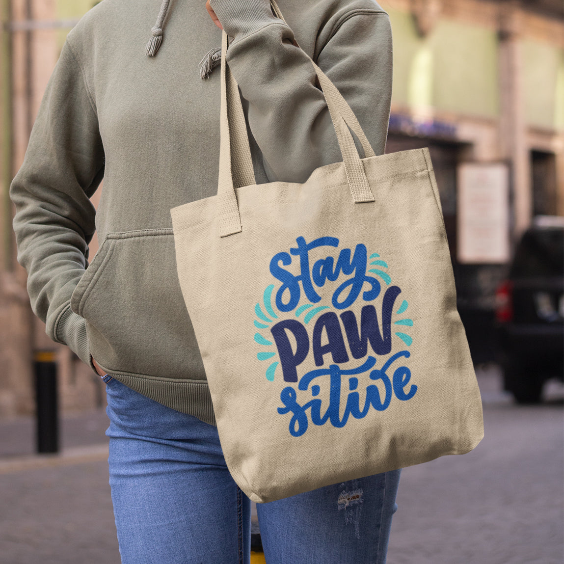 a woman carrying a tote bag that says stay paws alive