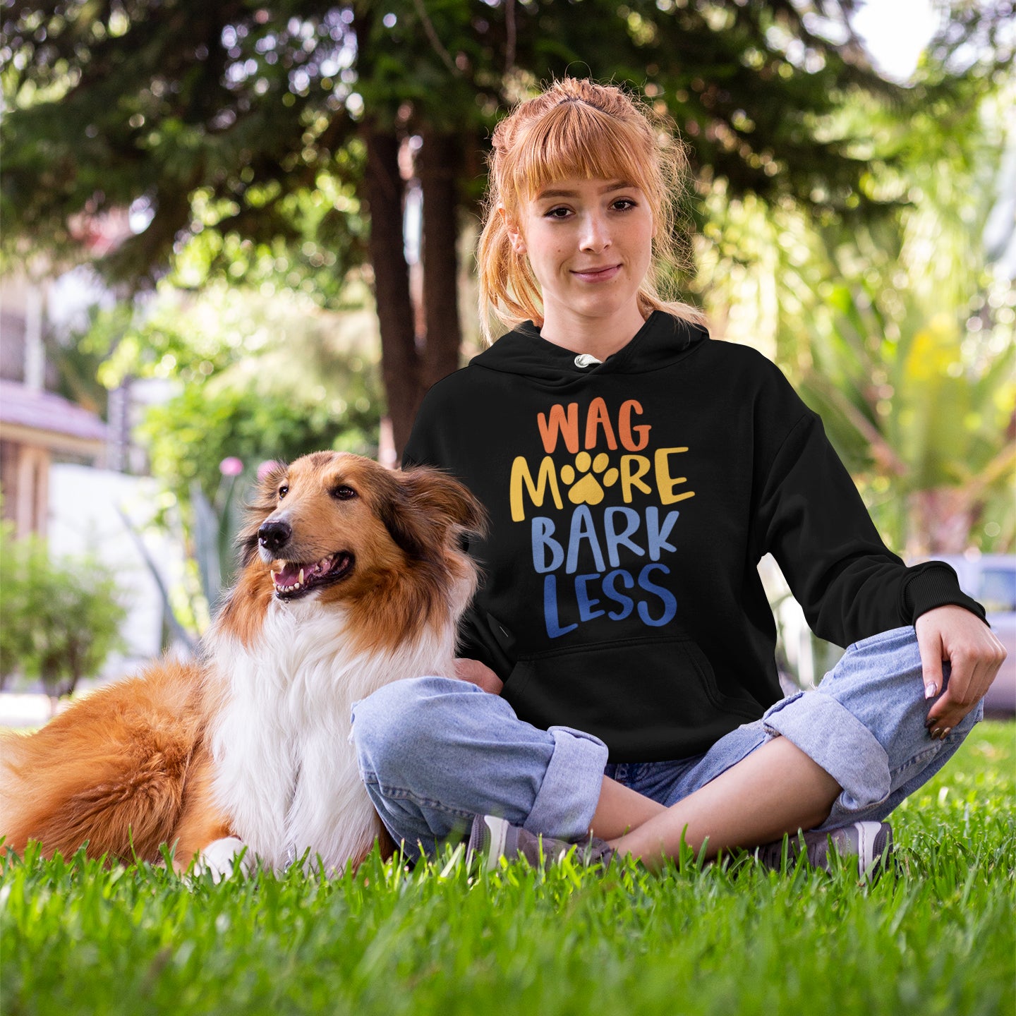 a woman sitting in the grass with a dog