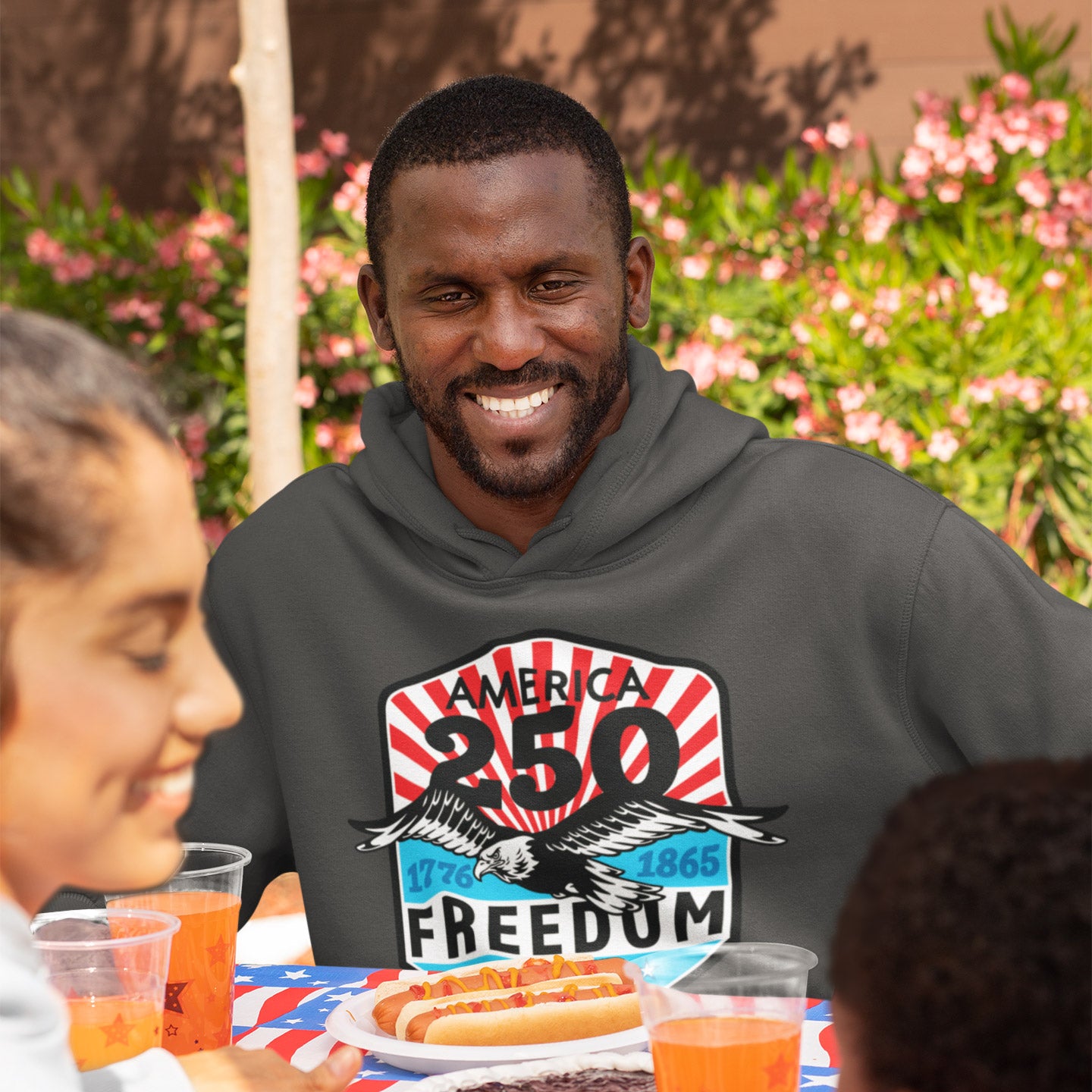 a man sitting at a table with a plate of hotdogs