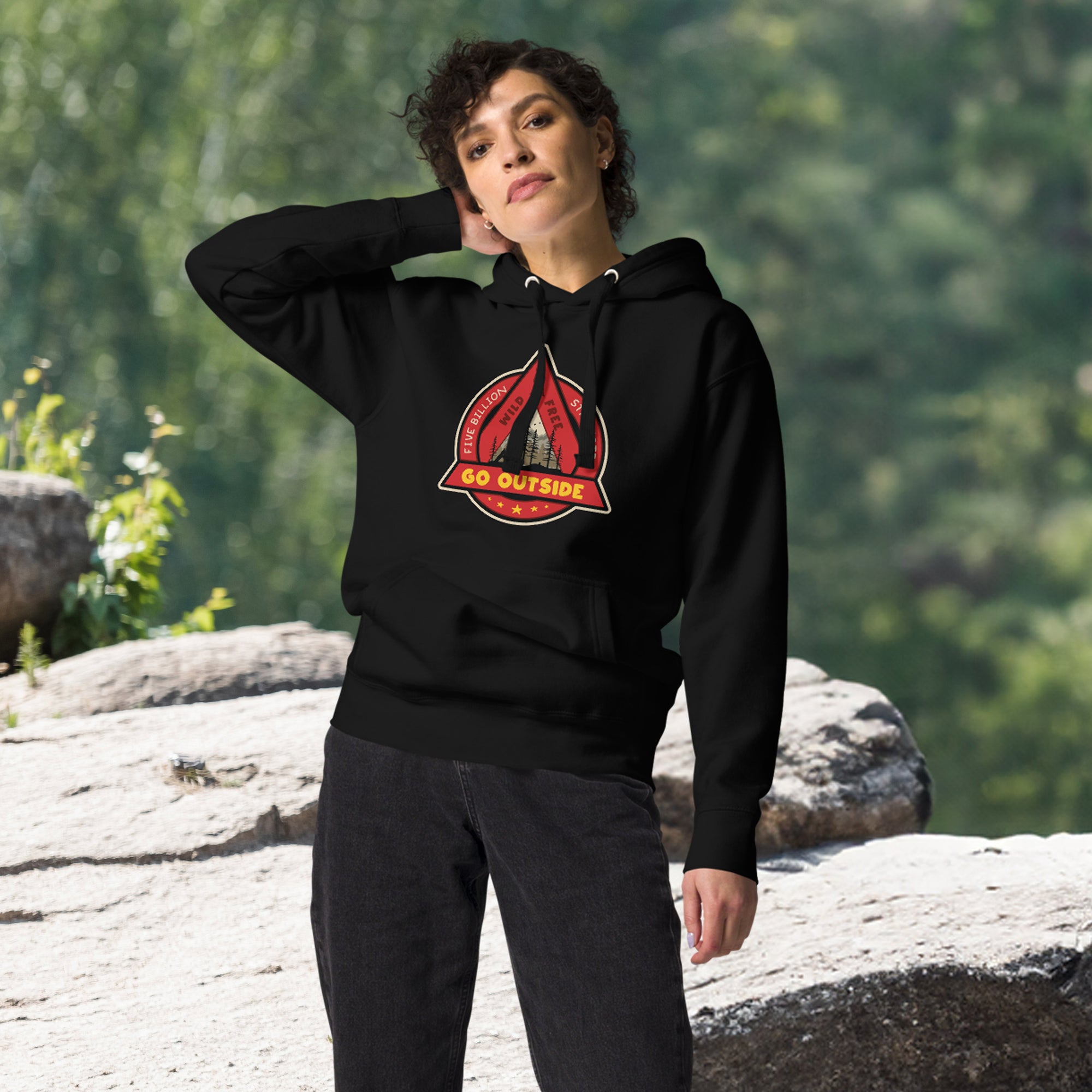 a woman in a black hoodie stands on a rock