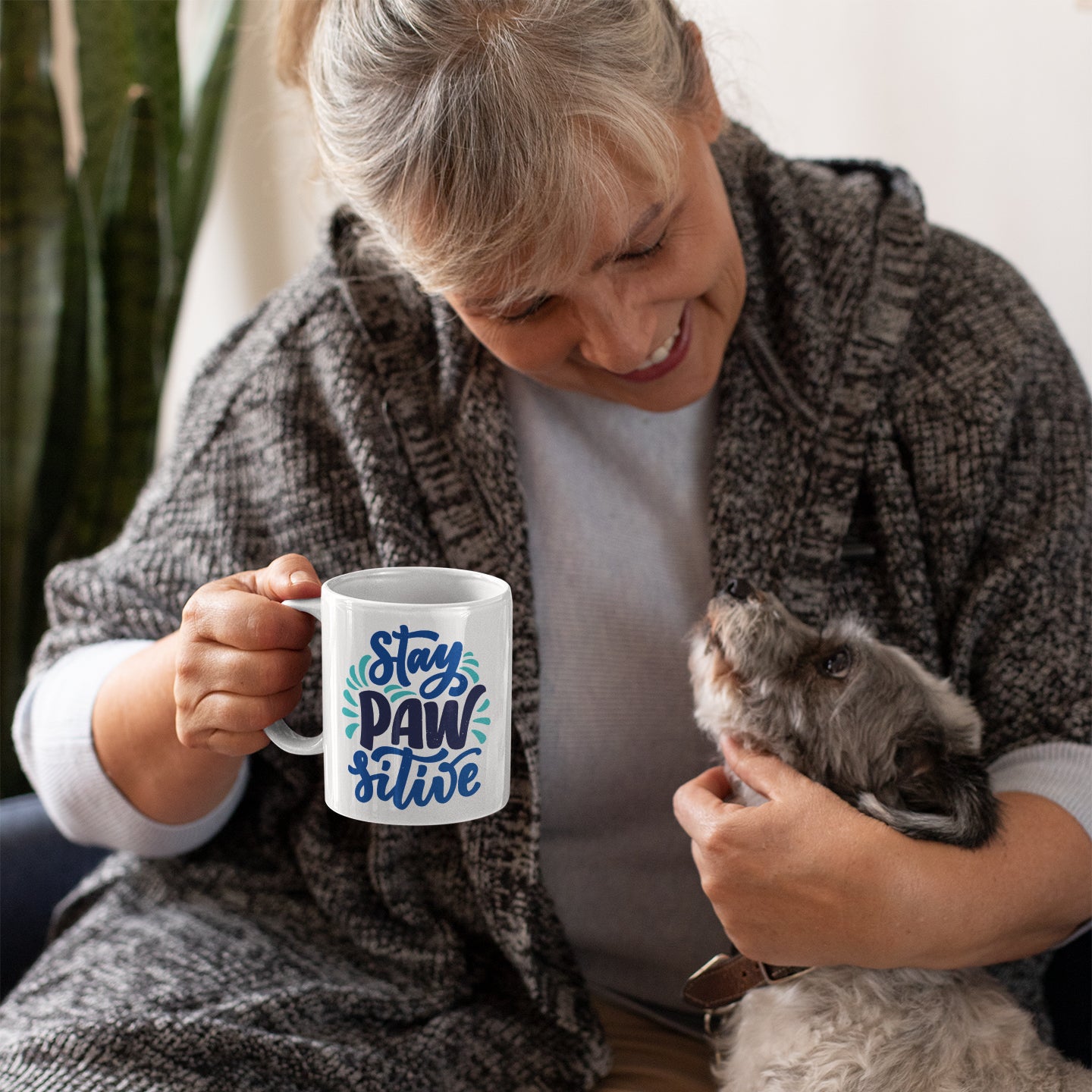 a woman holding a cat and a coffee mug