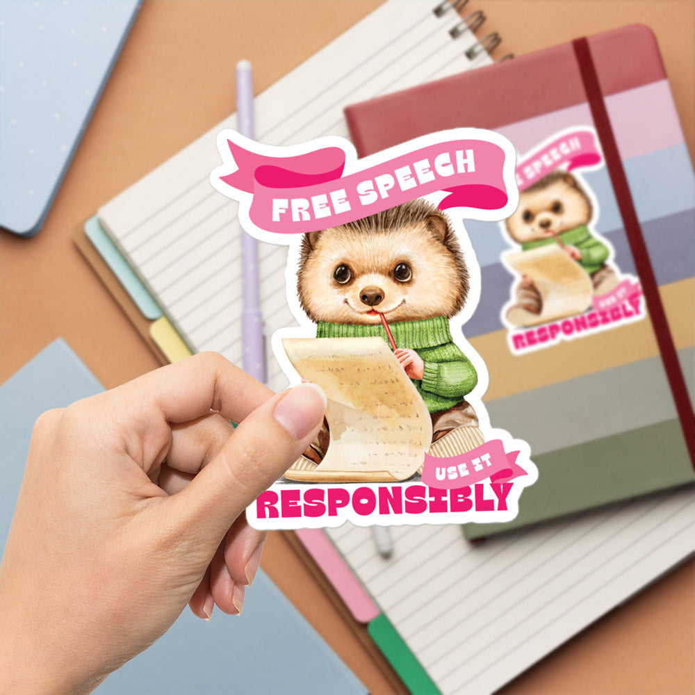 A hand is holding a sticker featuring a cute cartoon hedgehog wearing a green sweater and holding a piece of paper, with the text "FREE SPEECH USE IT RESPONSIBLY" on it.