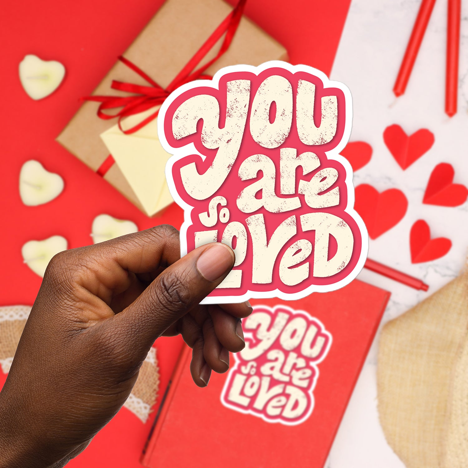 a hand holding a sticker that says you are loved