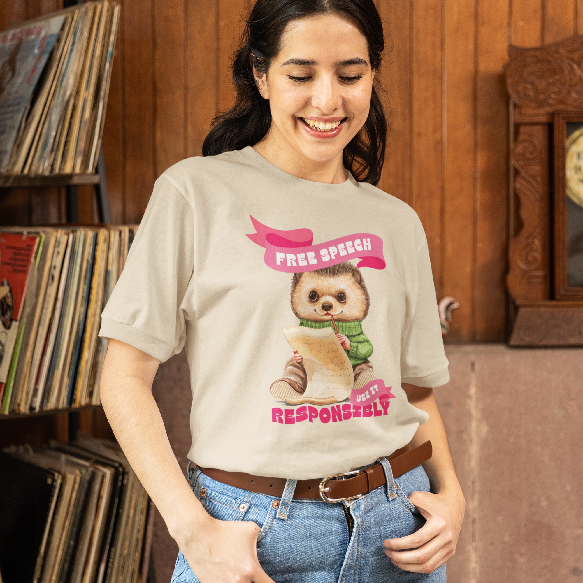 A woman wearing a t-shirt with a cartoon sloth holding a sign that says "Free Speech Responsibly" and smiling.