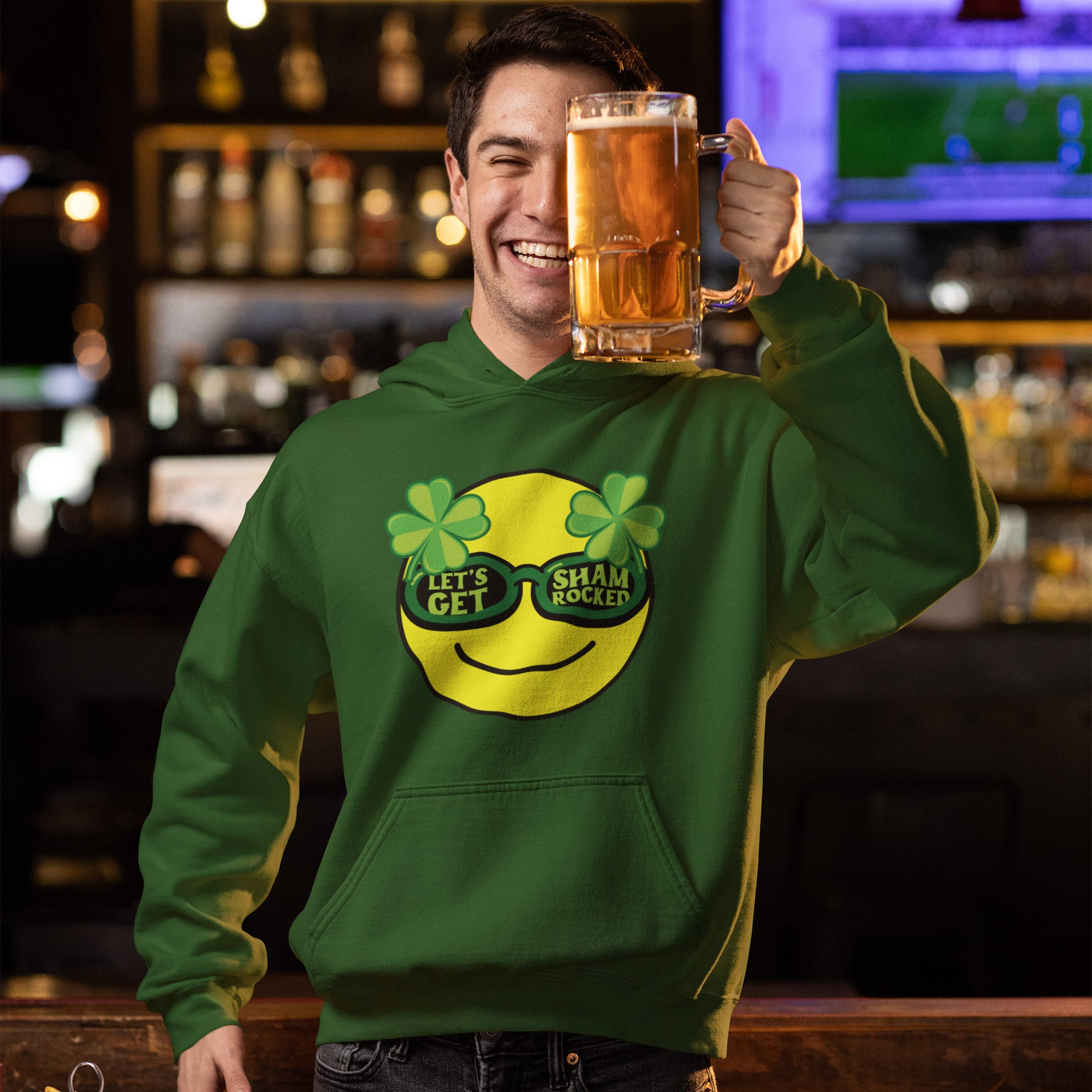 a man in a green hoodie holding a mug of beer