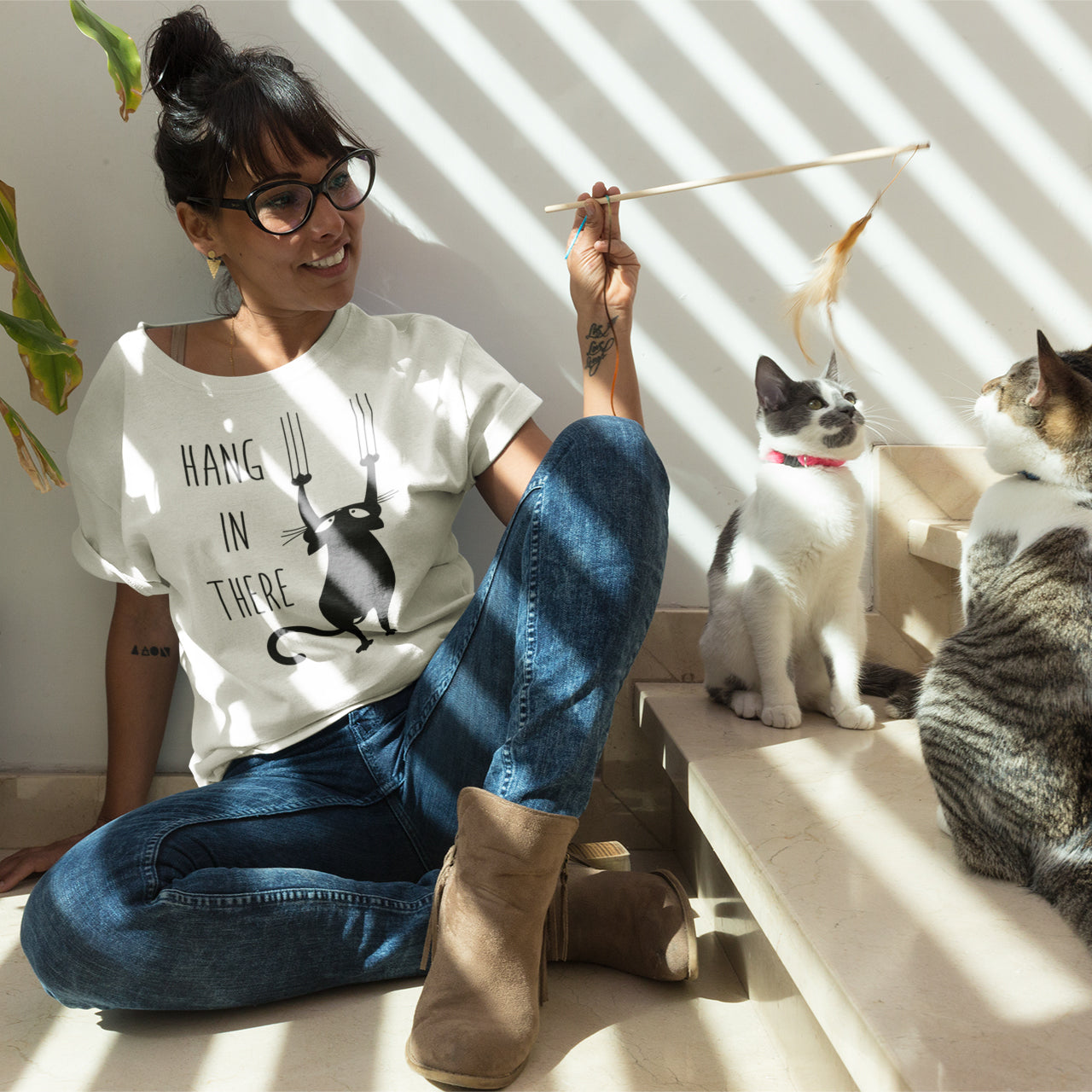 a woman sitting on the ground with two cats