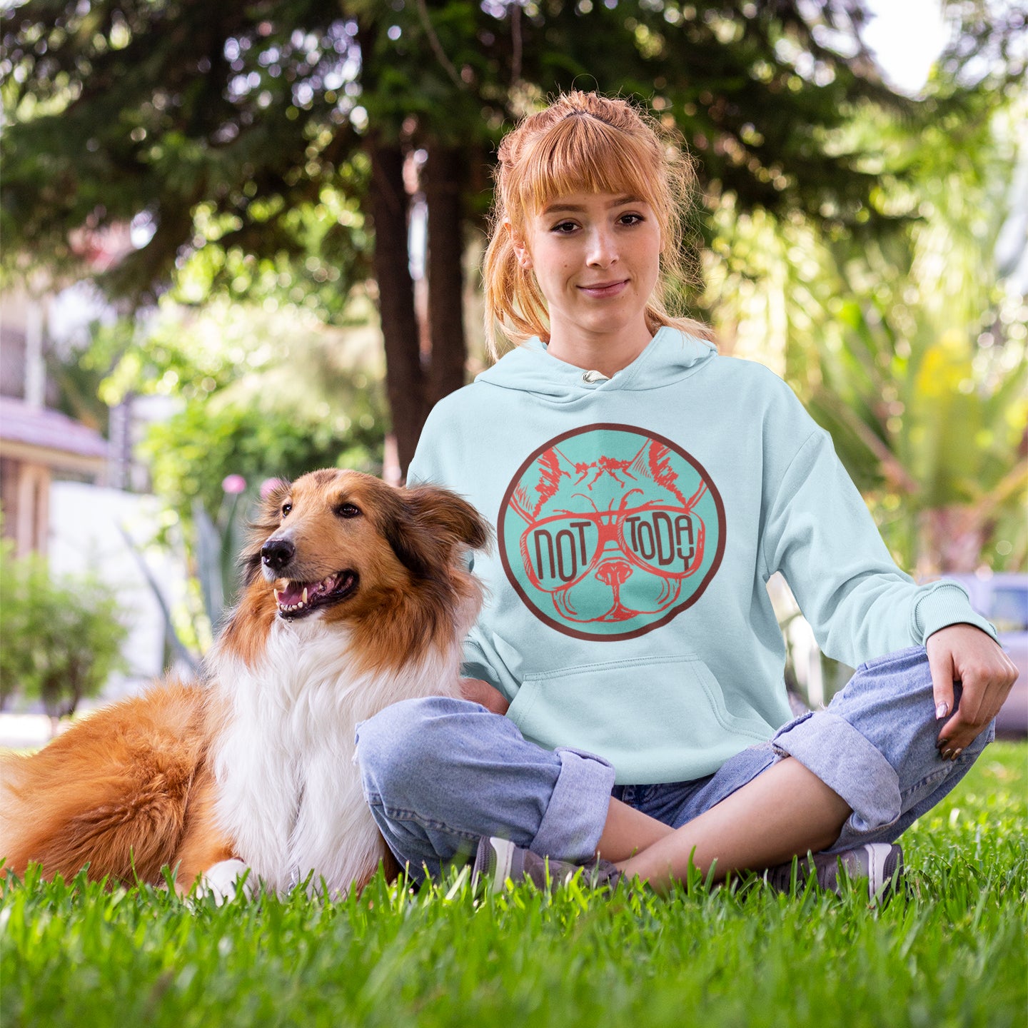 a woman sitting in the grass with her dog