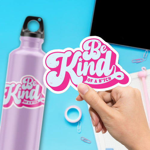 a hand holding a sticker that says be kind of a bitch