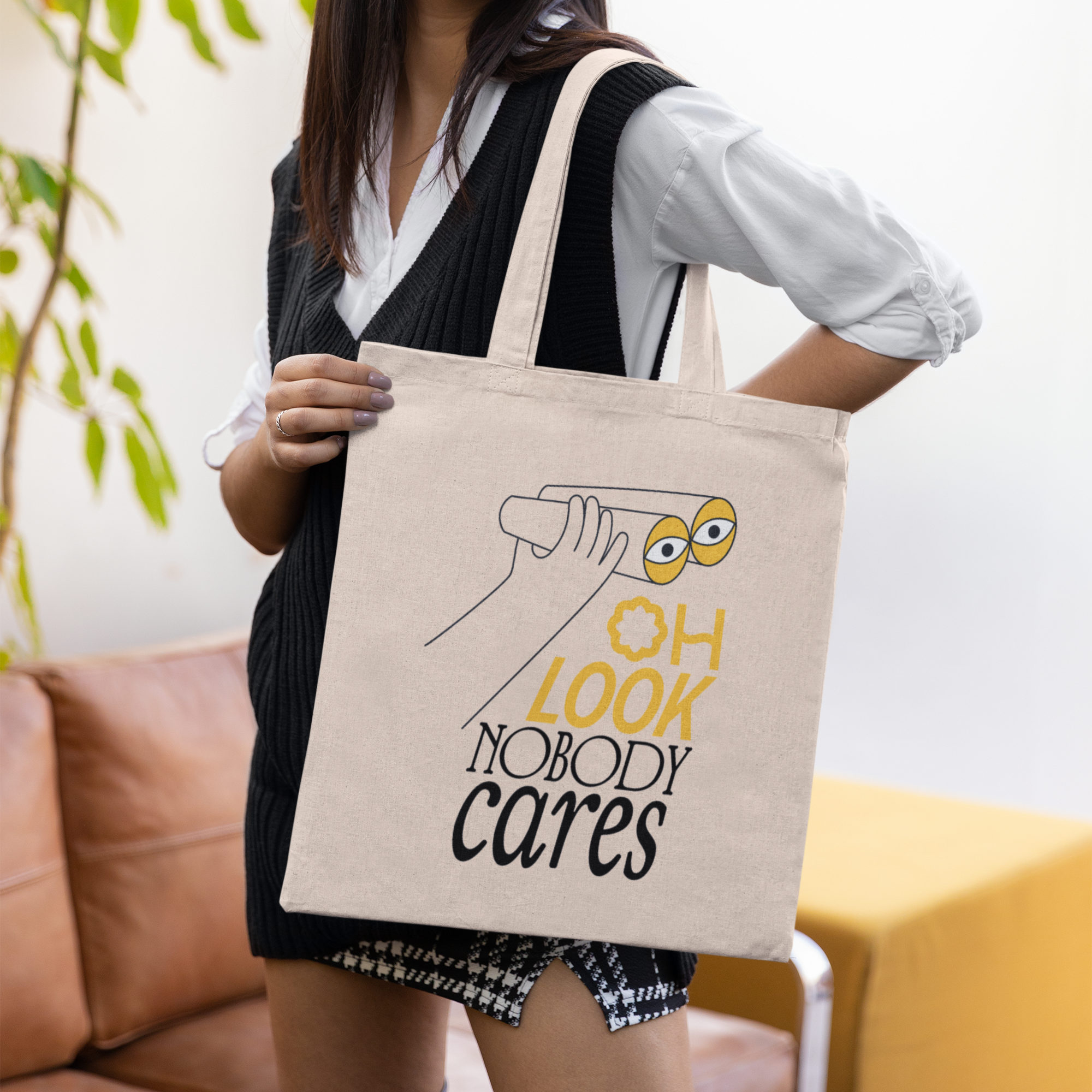 a woman holding a tote bag that says oh look nobody cares